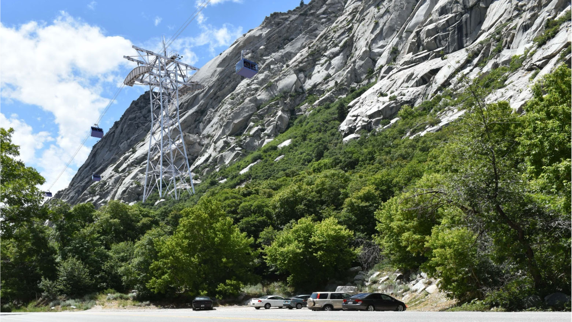 A tower to suspend a ski gondola soars above mountain cliffs. 