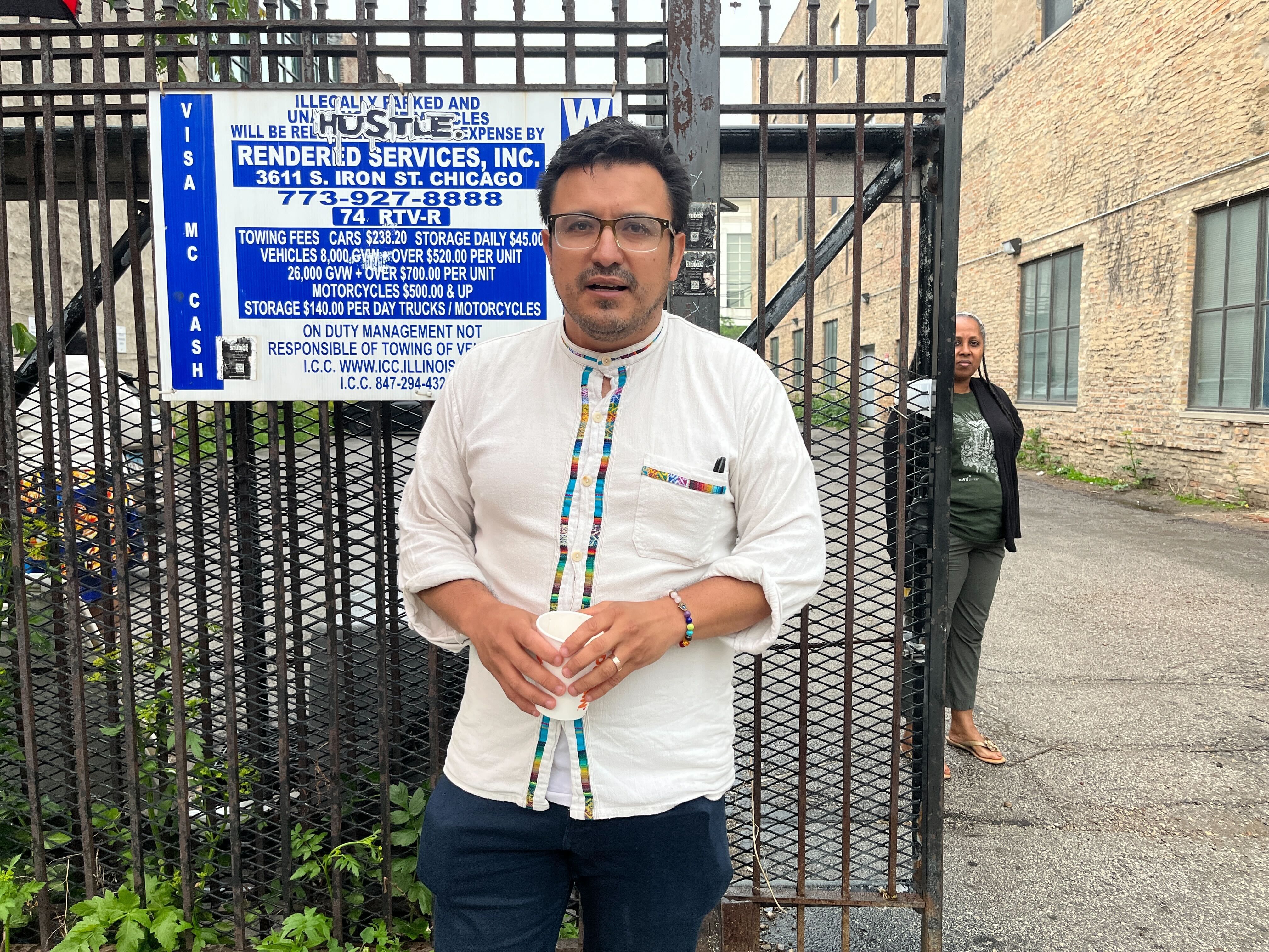 Photo of a man standing on a sidewalk talking. 