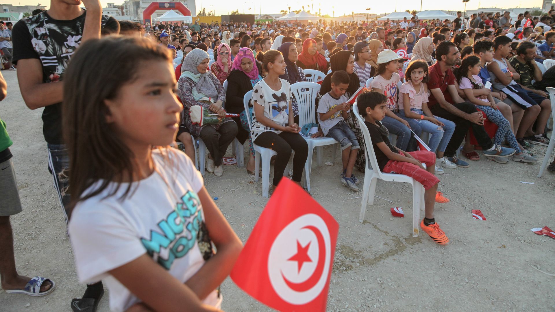 A little girl holds the flag of Tunisia