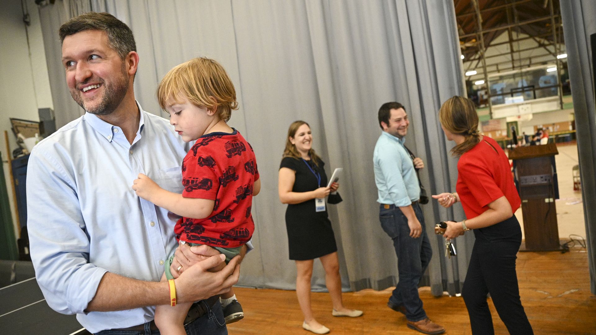 Democrat Pat Ryan, wearing a pale blue button down shirt and jeans, holds a child while campaigning.