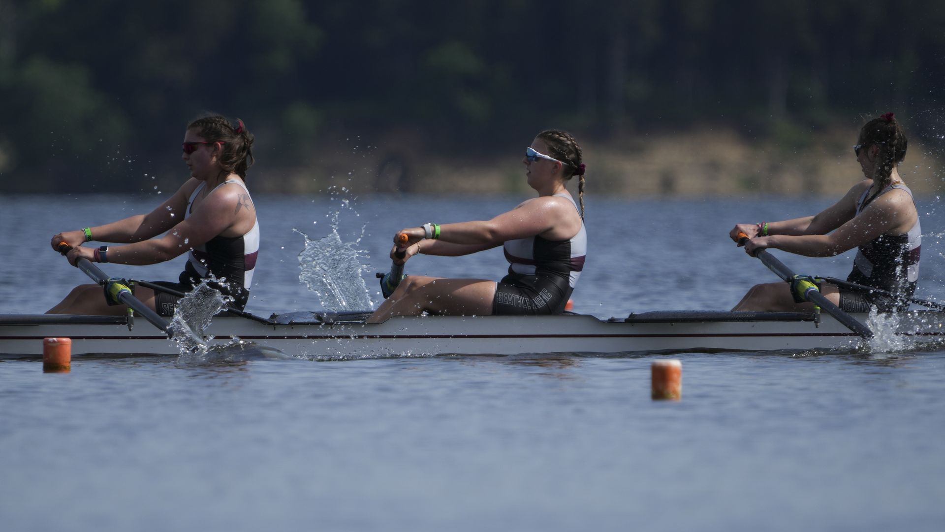 Three rowers on a women's crew team on the water. 