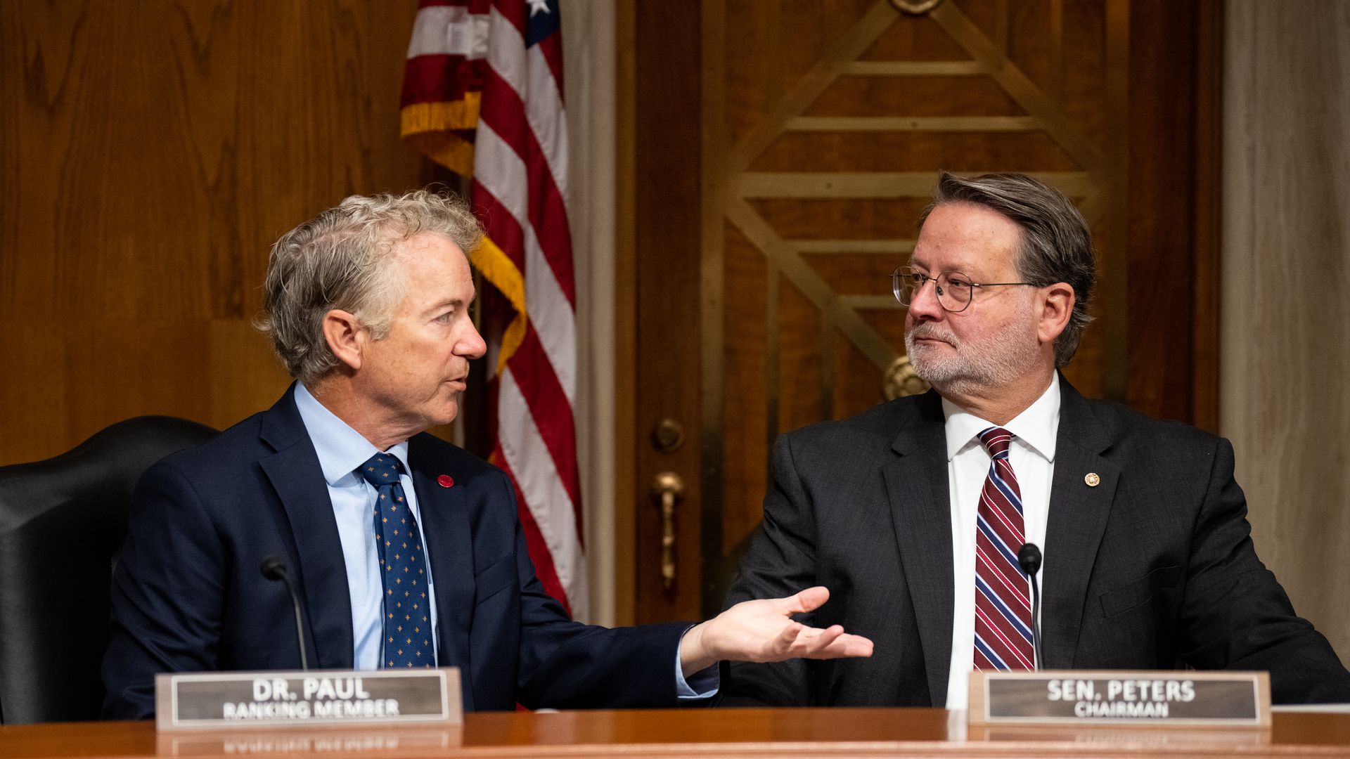 Photo of senators Rand Paul and Gary Peters at a dais.
