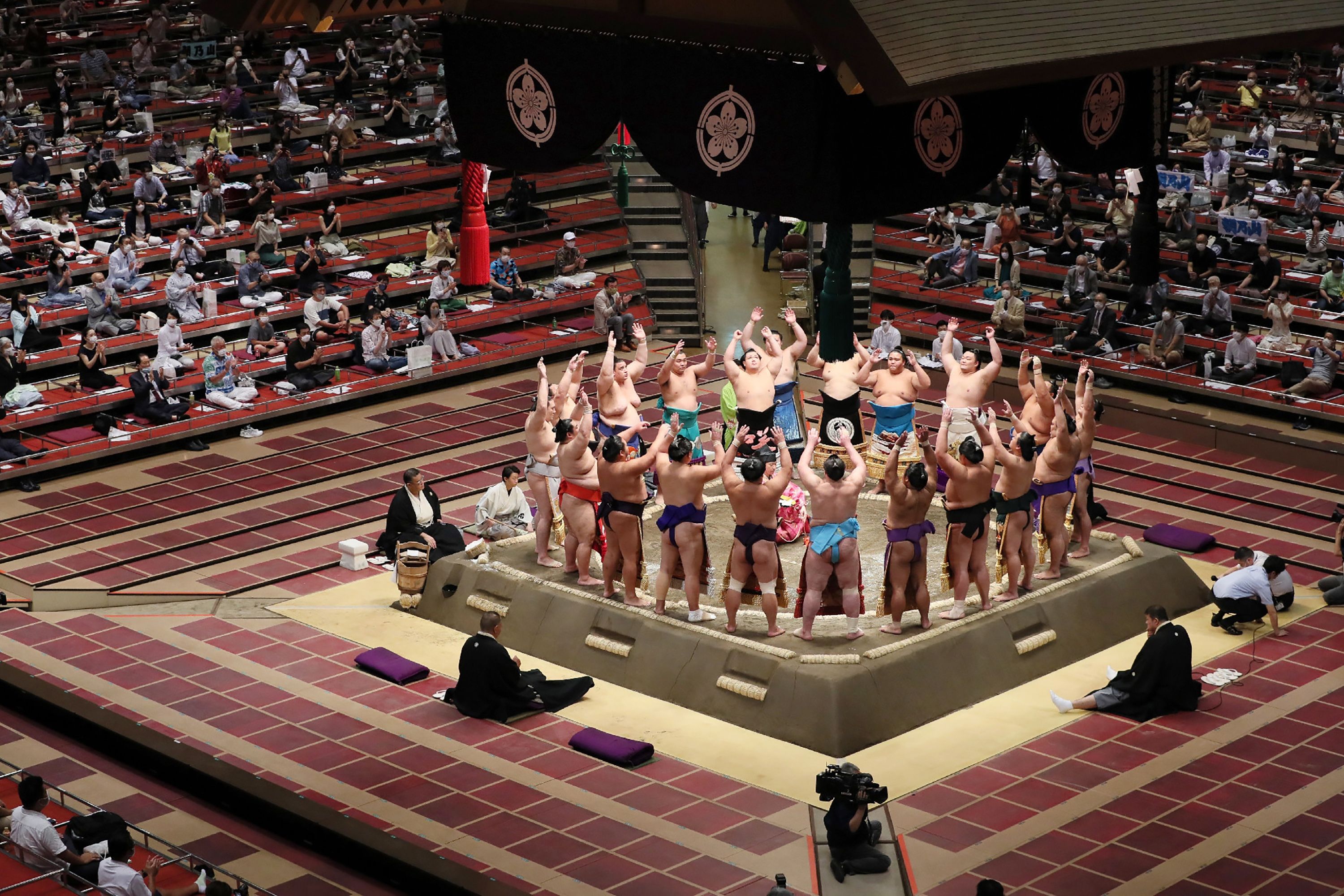 People sit apart to observe social distancing while watching wrestlers perform a ceremony ahead of their bouts during a new two-week sumo tournament in Tokyo