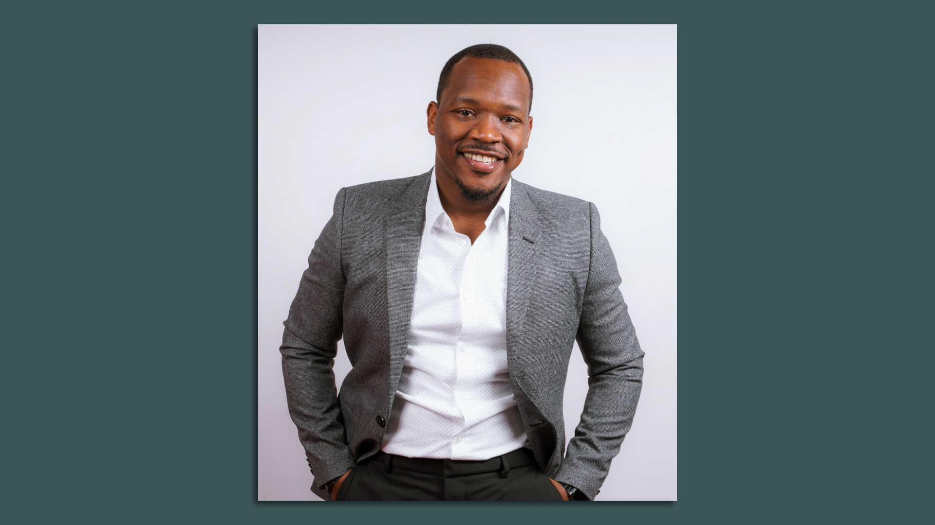 A headshot of Raheem Manning wearing a grey blazer.