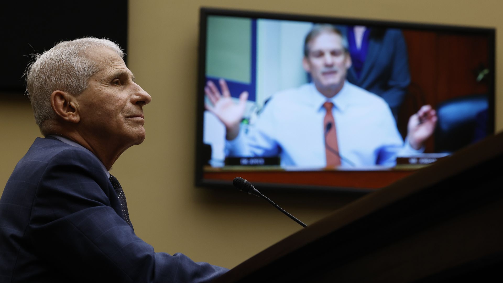 Photo of Anthony Fauci next to a screen with Jim Jordan on it.