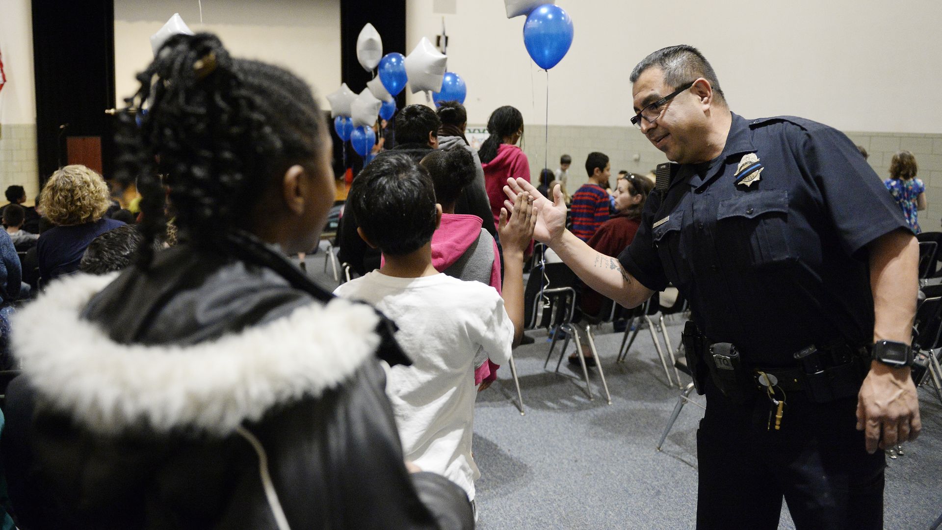 Denver police officer Adriel Torres high-fives students in an anti gang program in 2016. 