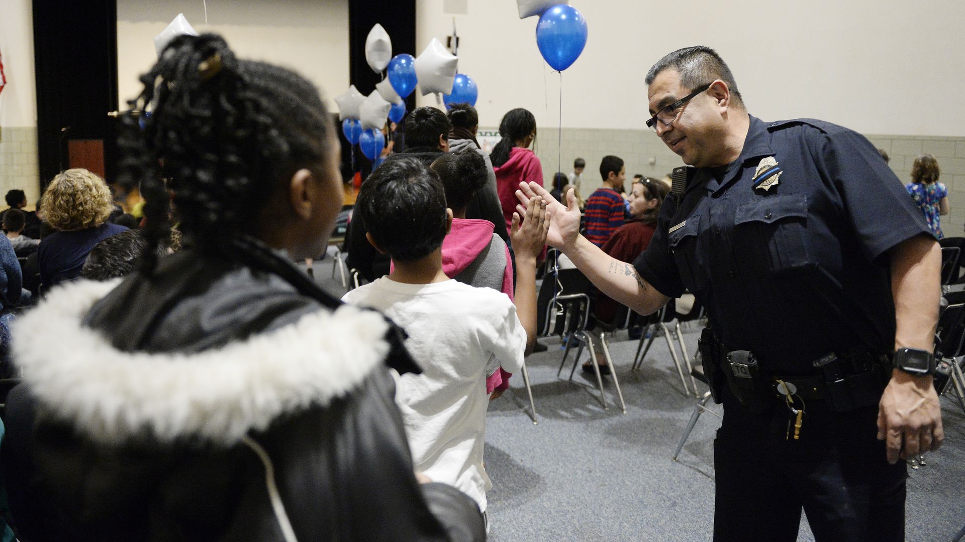 Denver police officer Adriel Torres high-fives students in an anti gang program in 2016.