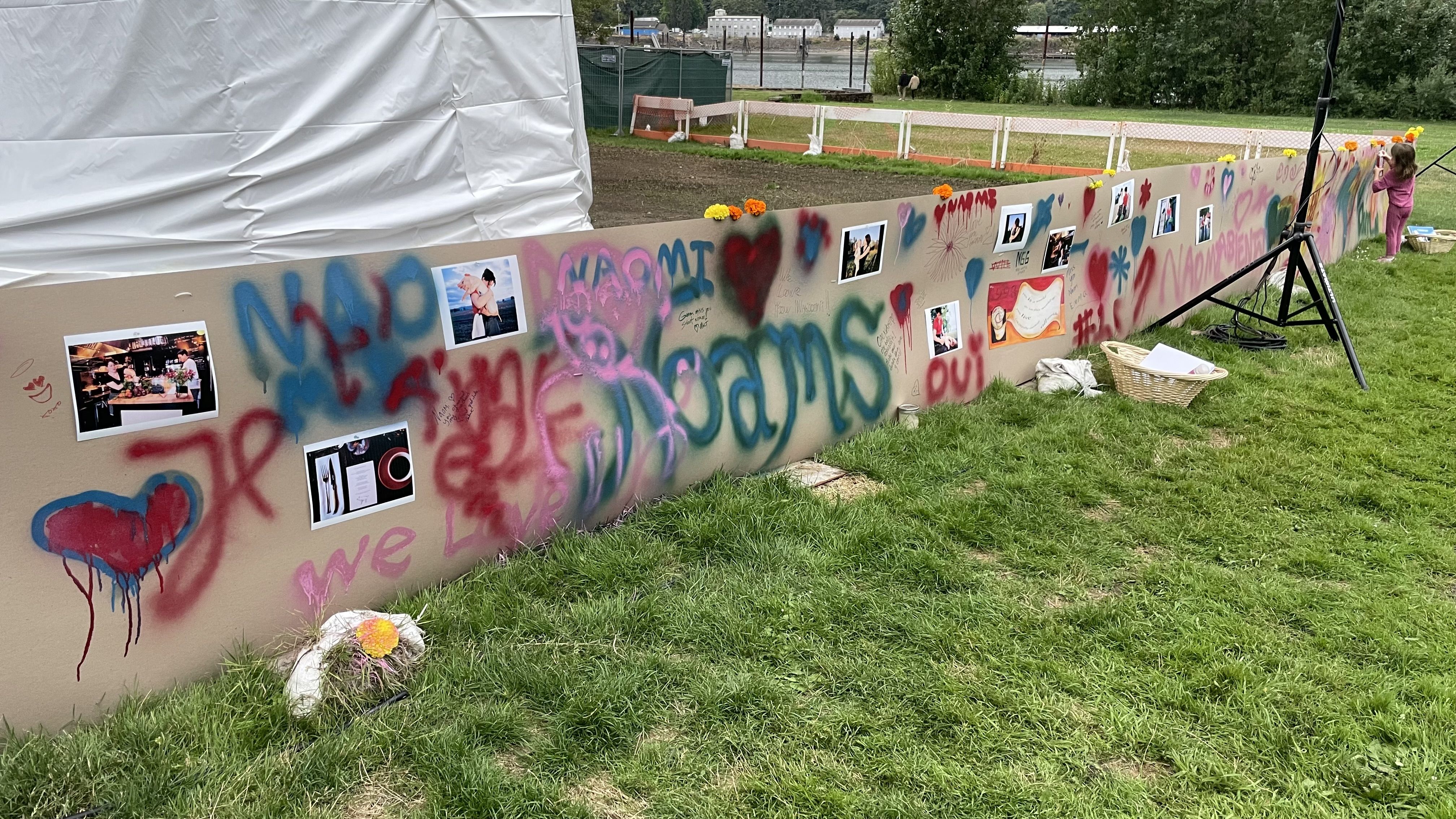 A photo of a concrete blockade spray painted with words like "Noams" and "Oui" as a memorial to the late-chef Naomi Pomeroy.