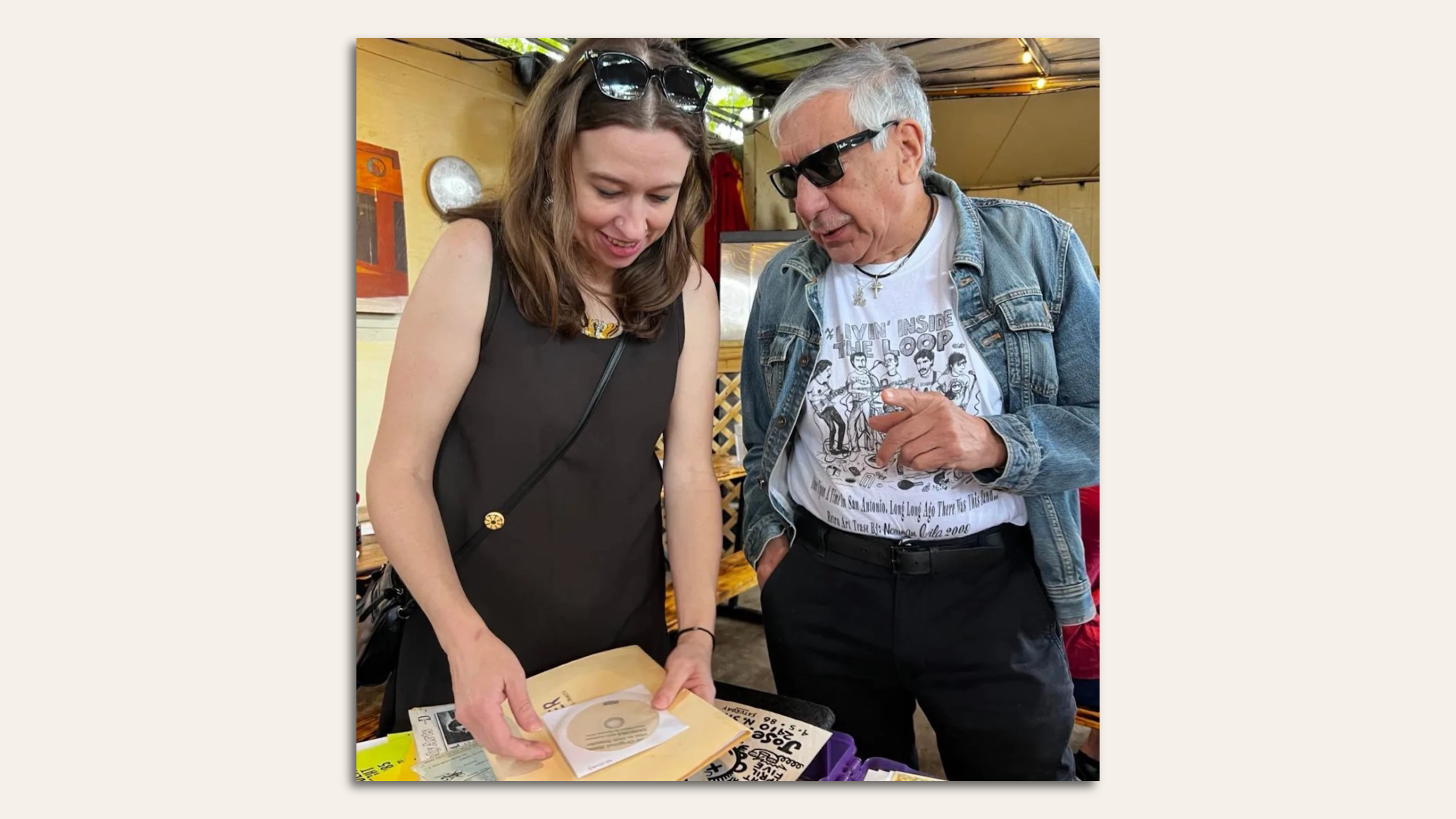 Abra Schnur looks over a small record while Norman Avila speaks to her.