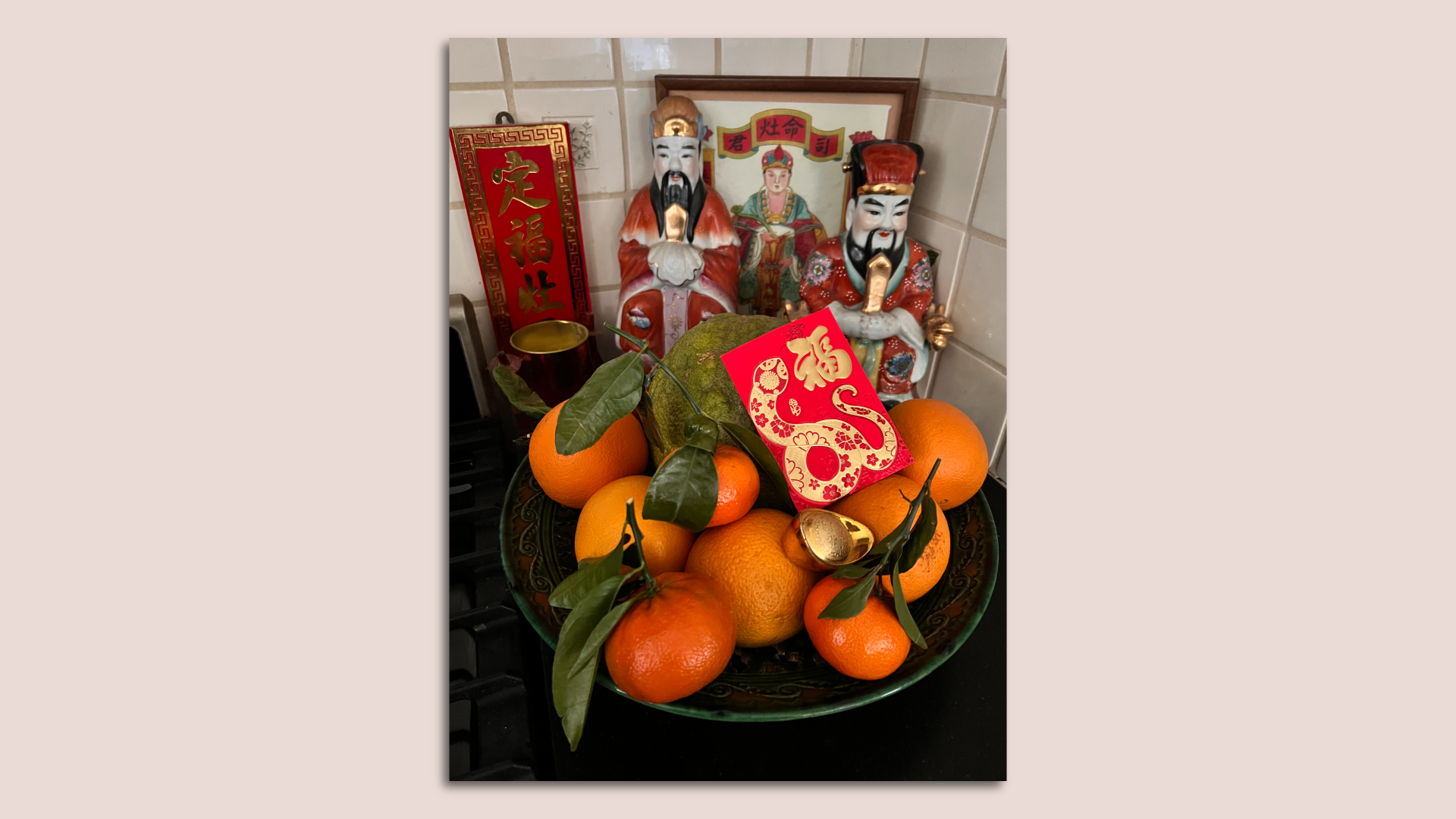 Lunar New Year centerpiece with oranges, a pomelo and a lucky money envelope that has a gold snake on it
