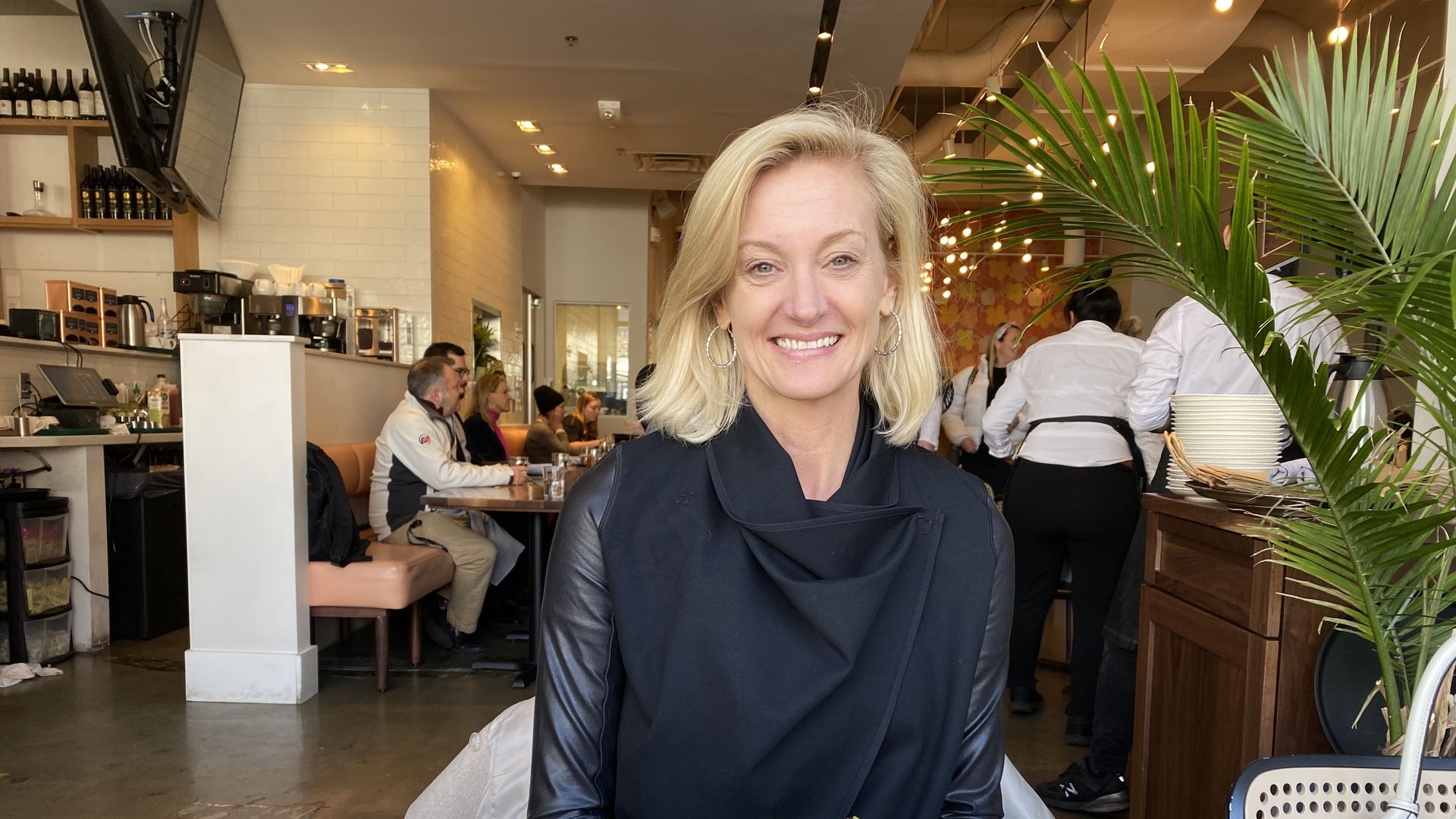 Krista Drobac sitting down at a restaurant. In front of her on the table is a cup of coffee and a plate of Lebanese fried rice.