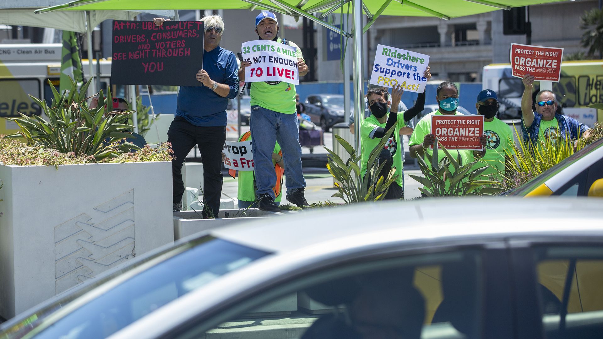 Photo of a car driving by a crowd of protesters with signs pushing for the right to organize