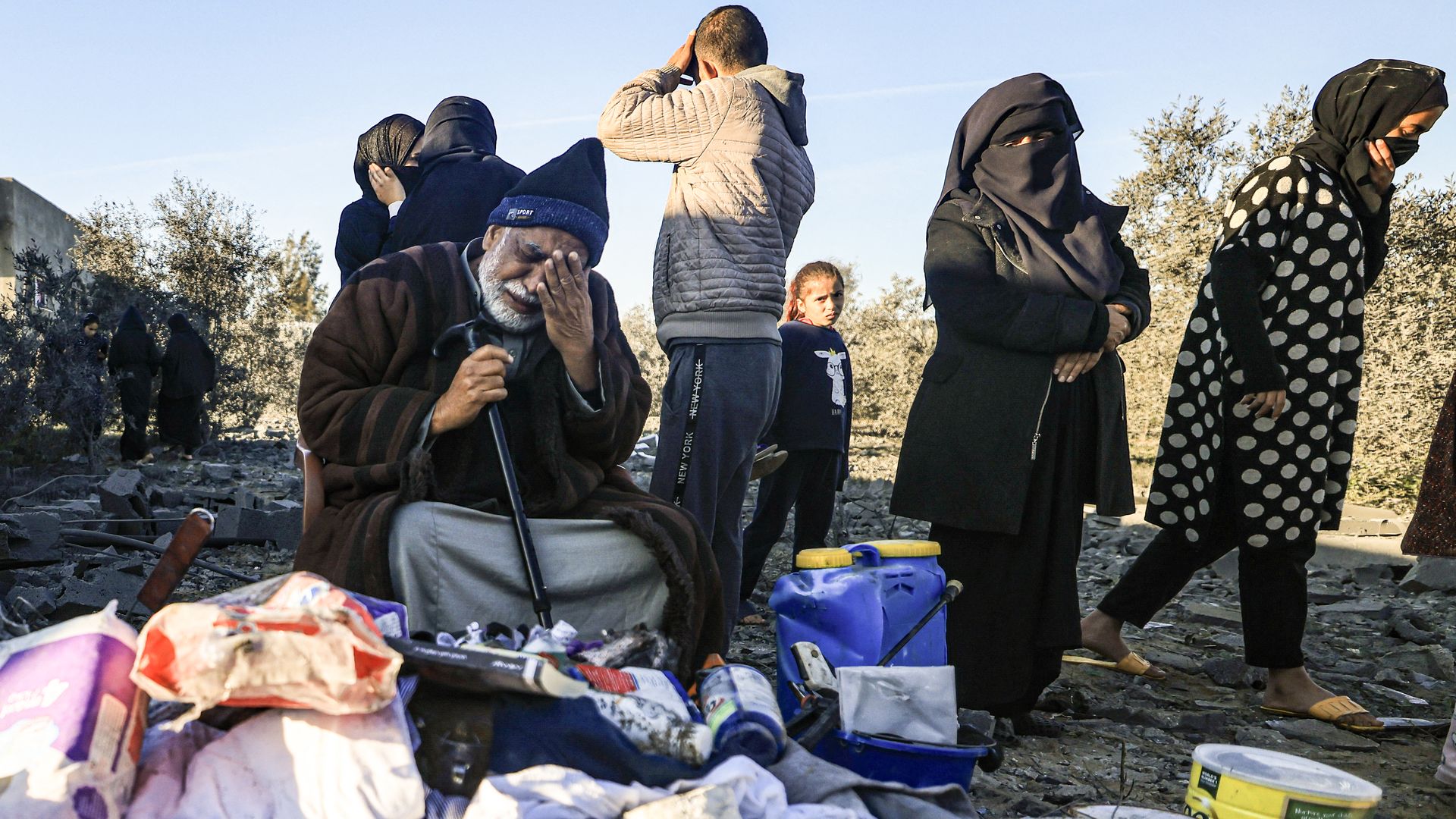 A displaced Palestinian man reacts as he sits among objects salvaged from a house that was used as a shelter by his extended family members, many of whom were reported killed when it was destroyed during an Israeli strike on Rafah in the southern Gaza Strip on January 7, 2024