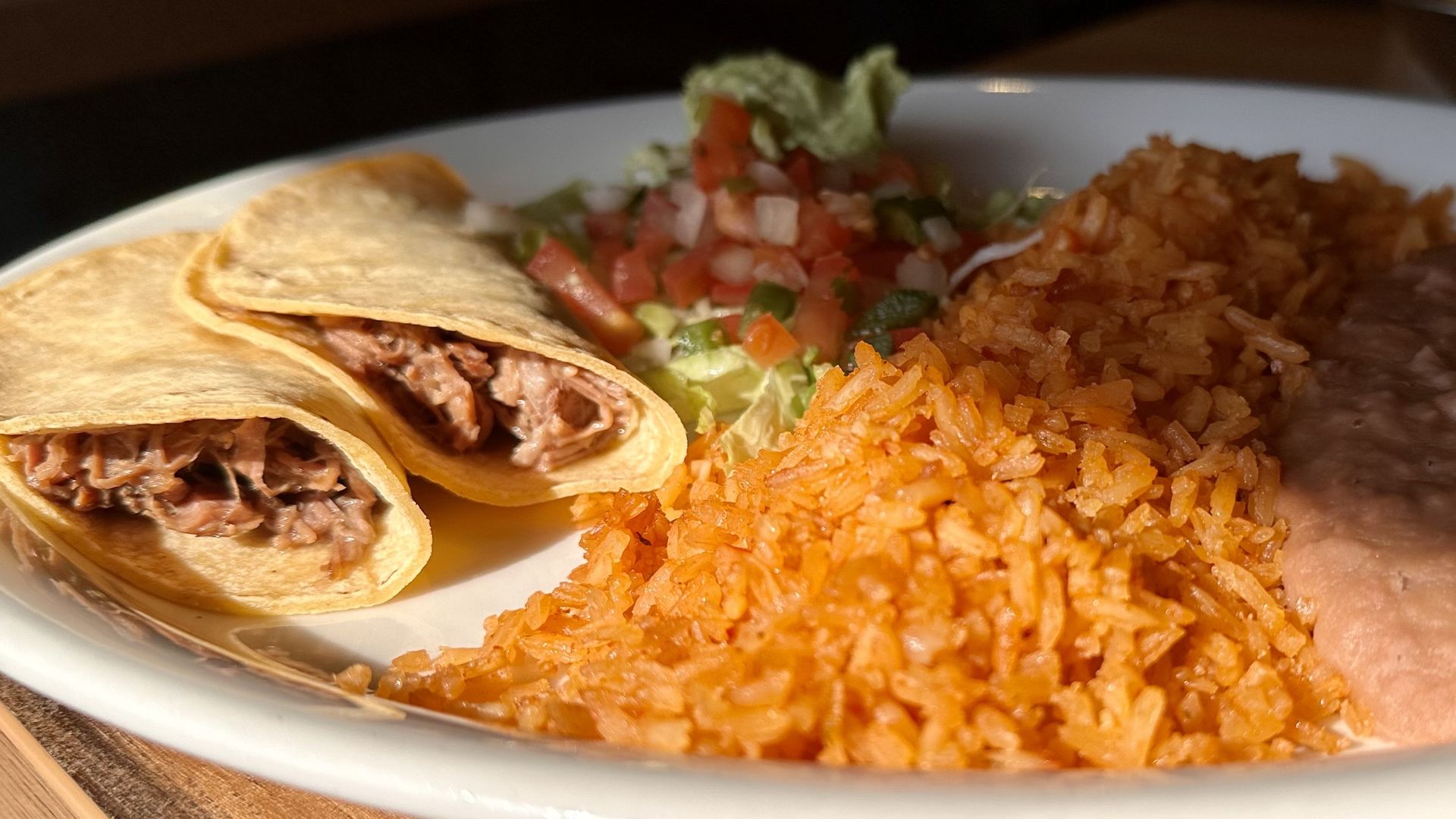 two tacos on a plate with rice and pico