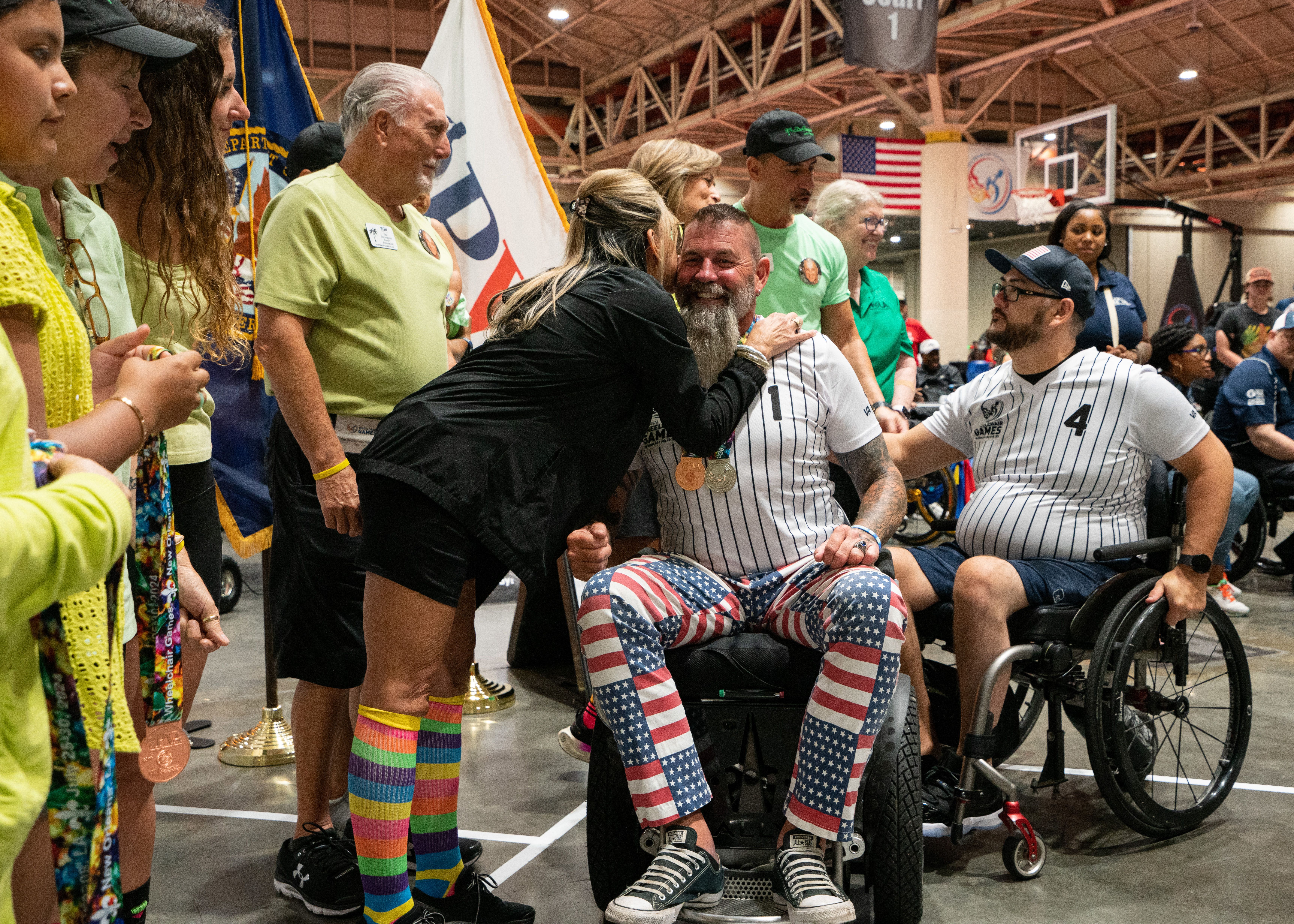 A person leans over to hug someone in a wheelchair.