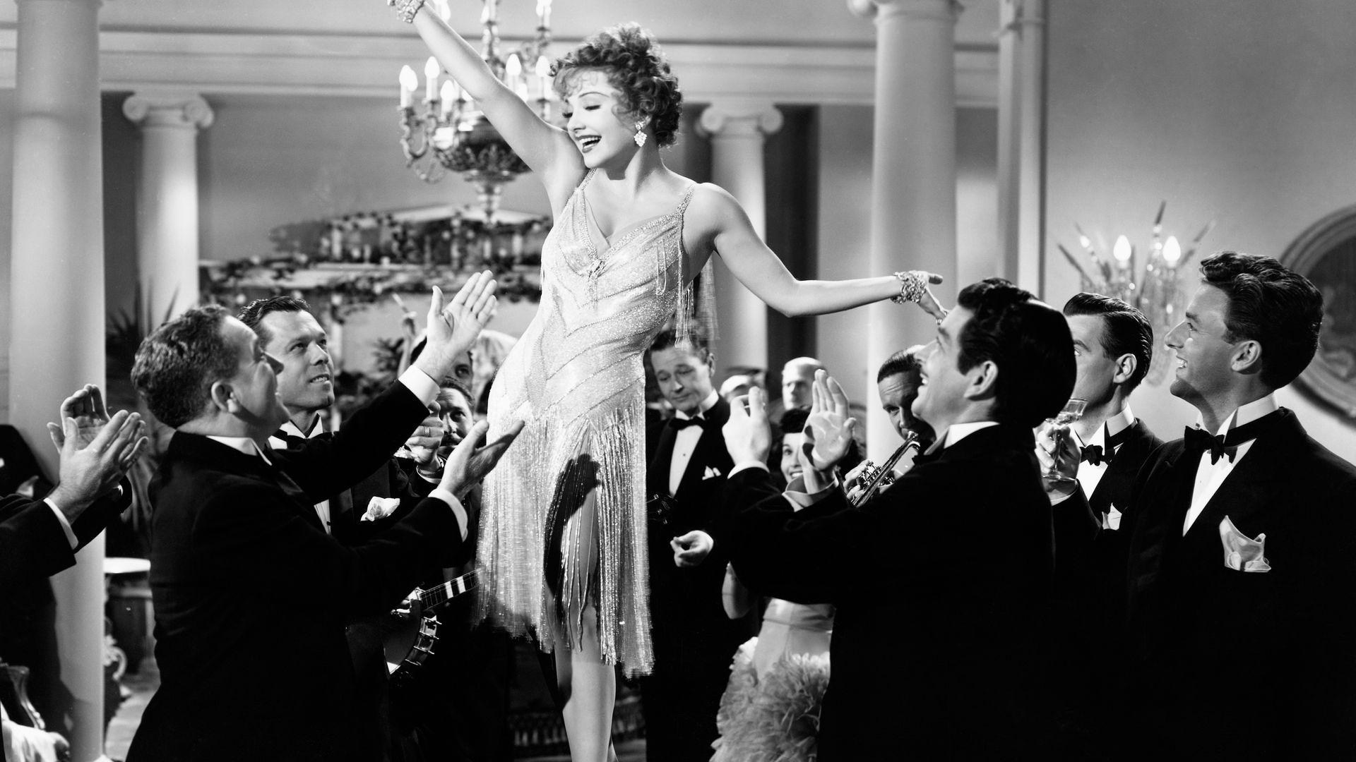 Anne Baxter's character Hannah Adams stands on a table to the delight of appreciative men in a party scene from the 1949 film You're My Everything.
