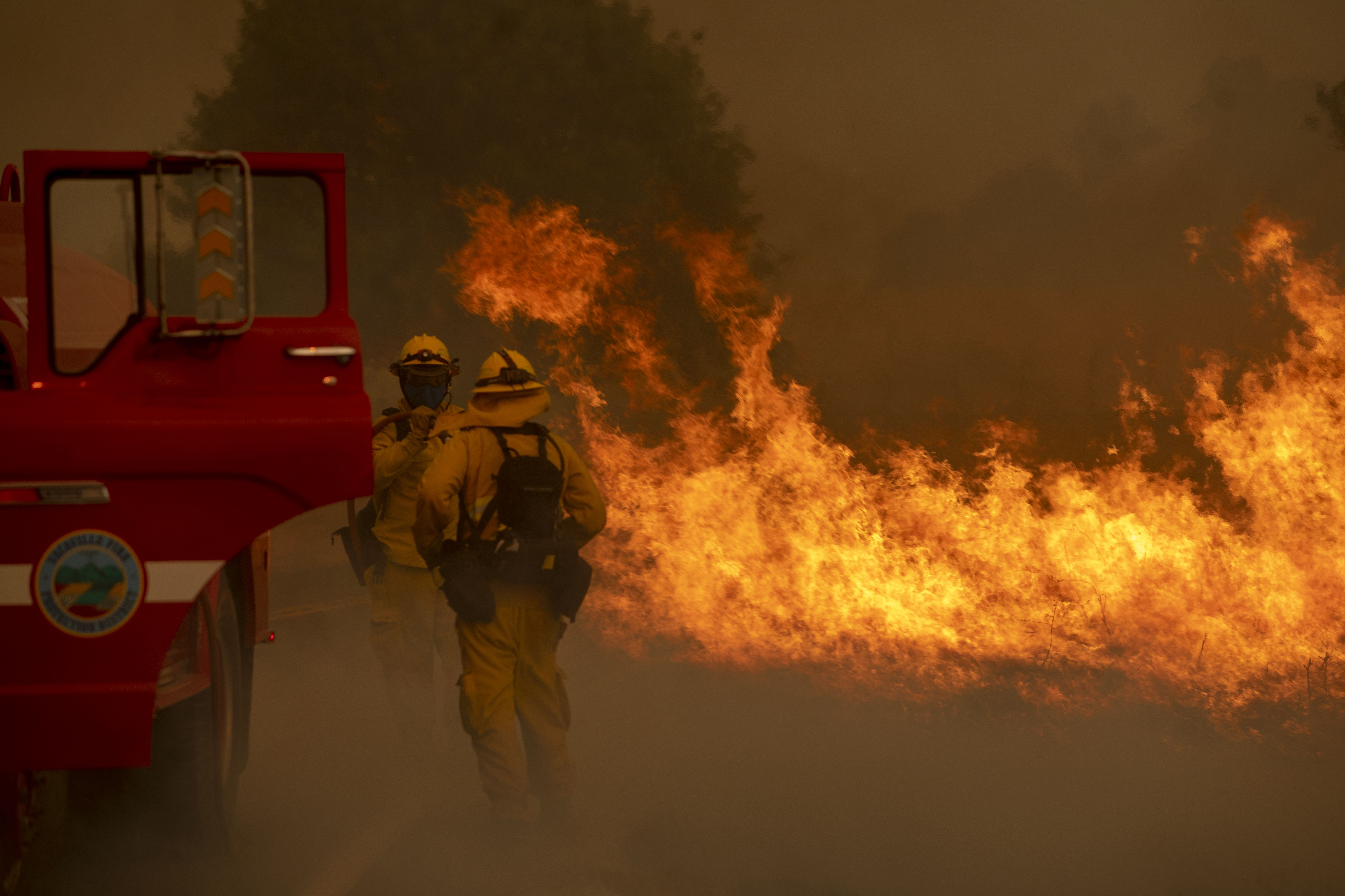  Firefighters attempt to stop a grass fire from jumping a road in Vacaville, Calif., Wednesday, Aug. 19