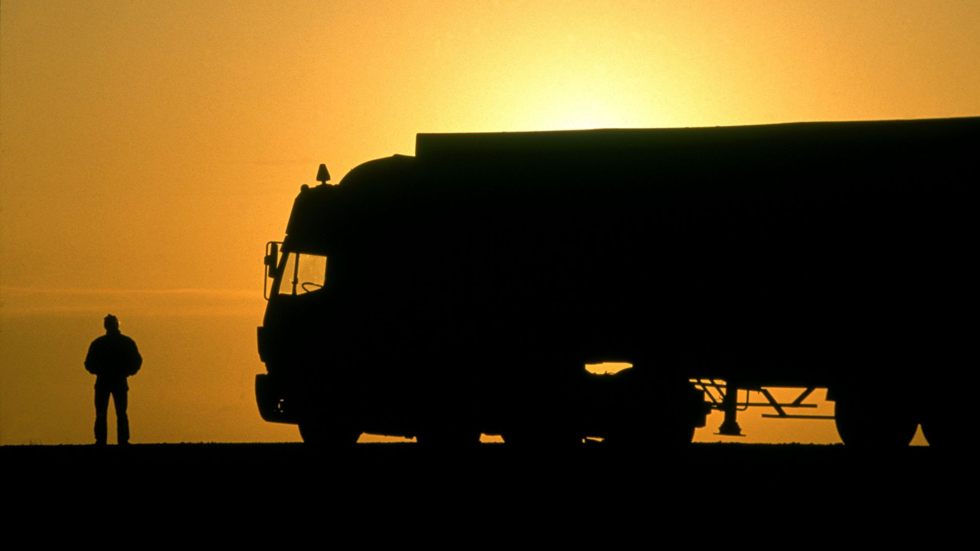 Truck driver with his truck in the sunset