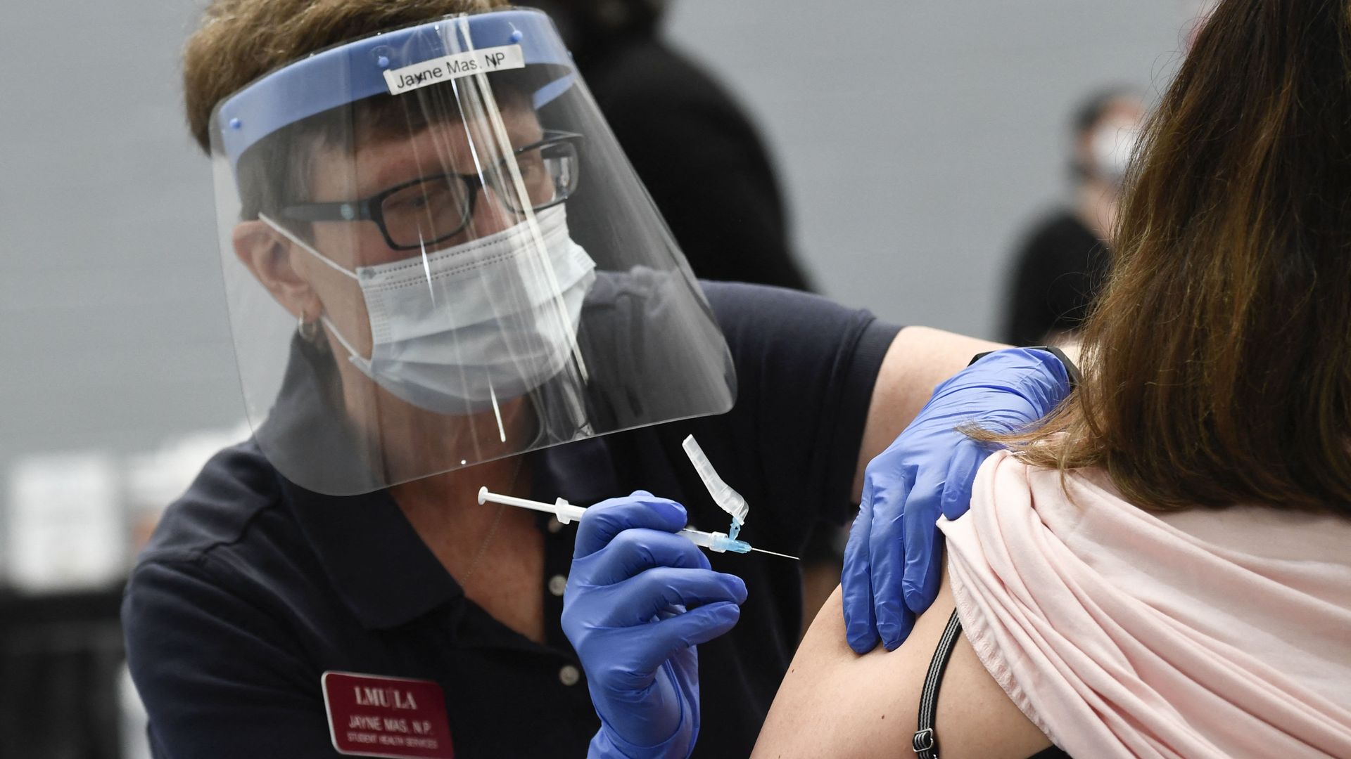 Photo of a masked nurse giving someone a vaccine shot