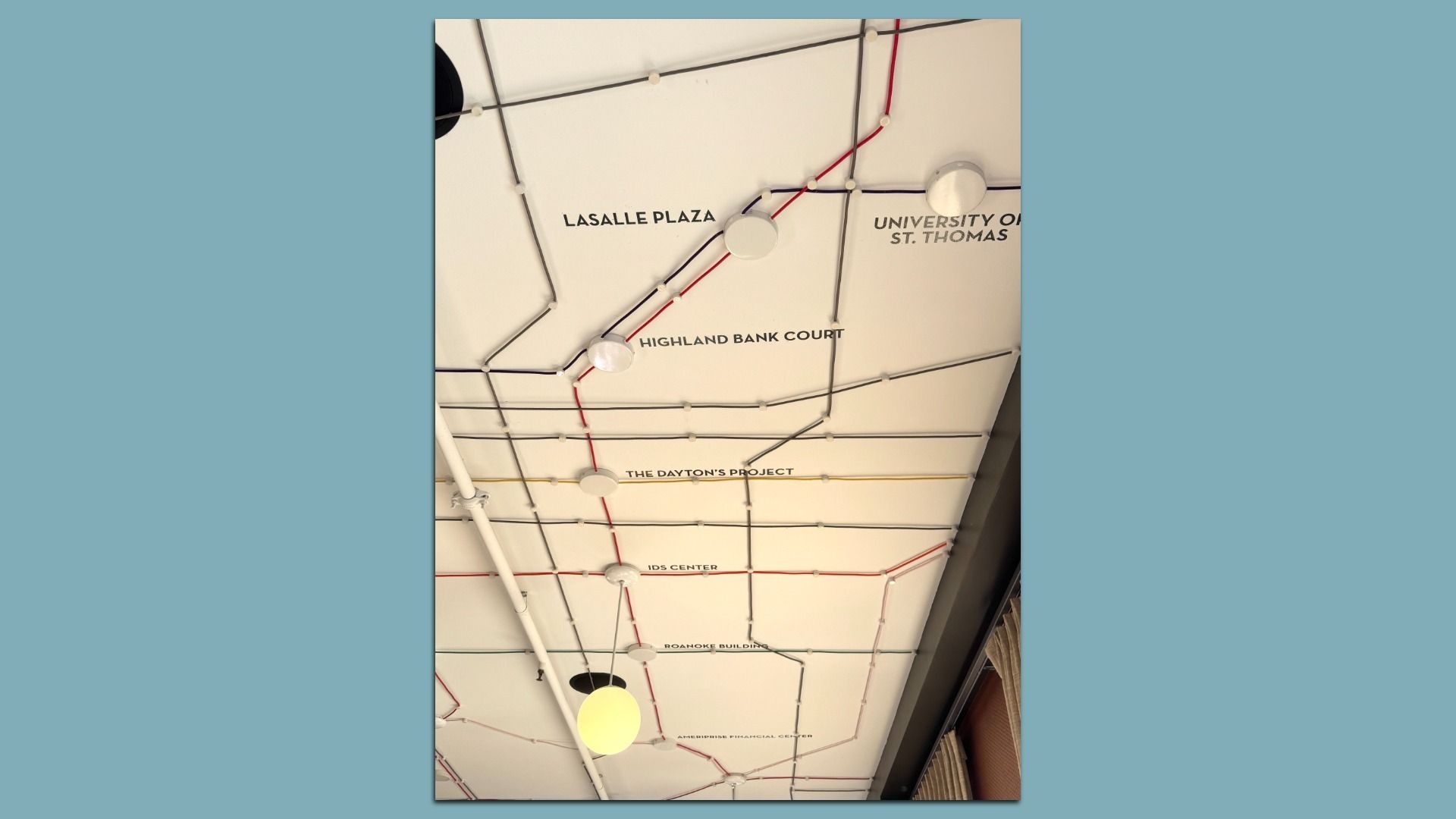 Ceiling map with a grid of white panels, black and red pipes, and circular lights. Labels include Lasalle Plaza, Highland Bank Court, The Dayton's Project, and IDS Center.