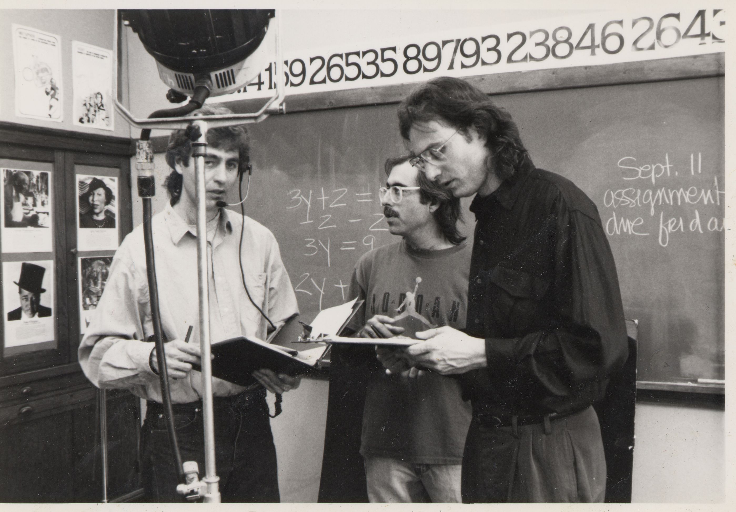Photos of three men talking around a film set 