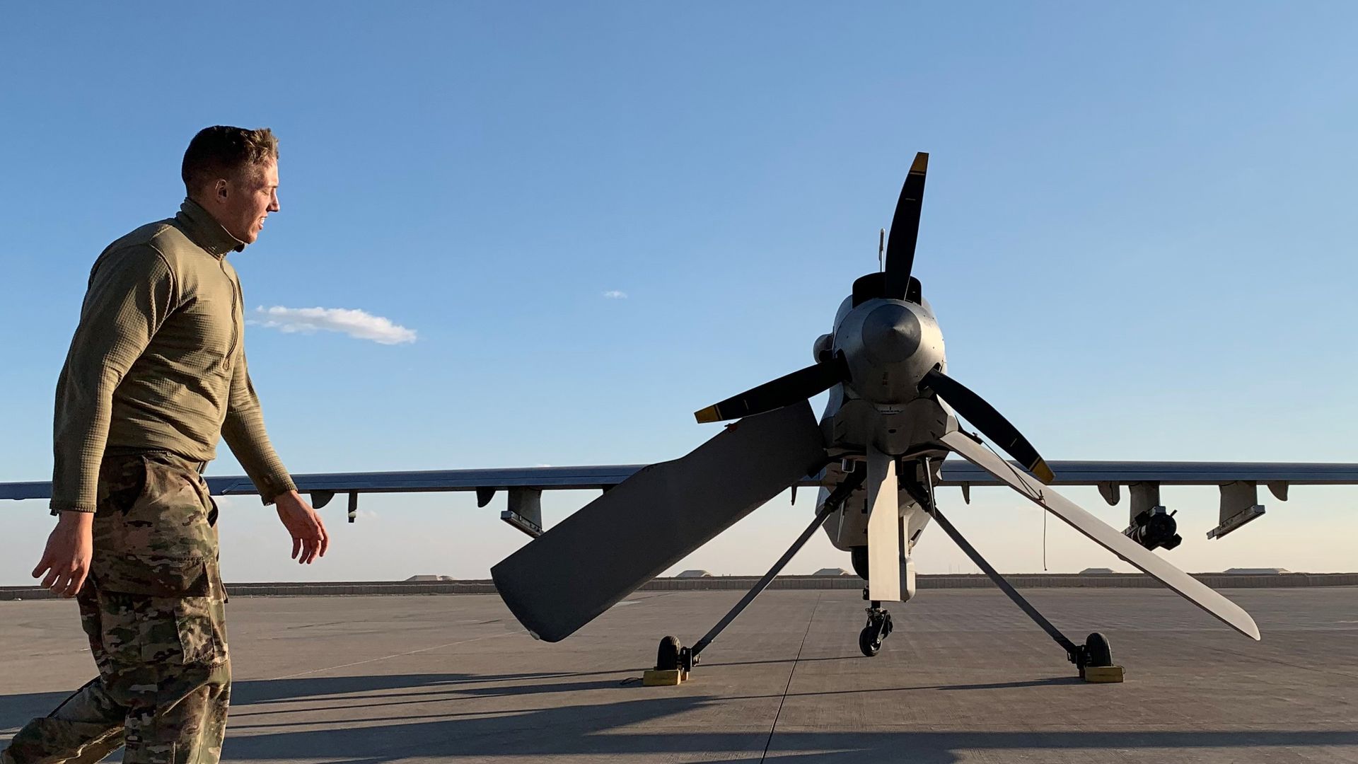 In this image, a US soldier in Iraq walks past a military plane