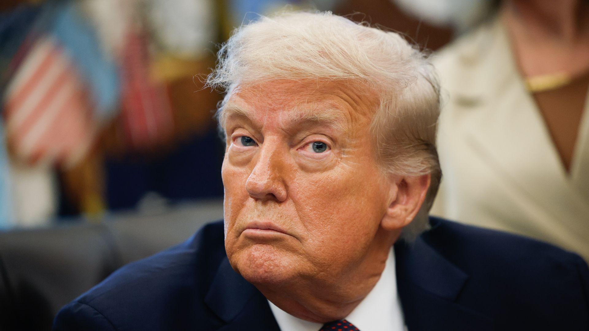 President Trump, wearing a navy jacket with a US flag pin, a white shirt and a blue tie with pink dots on it, answers questions from reporters after signing a Presidential Memorandum in the Oval Office on September 15, 2025 in Washington, DC. 