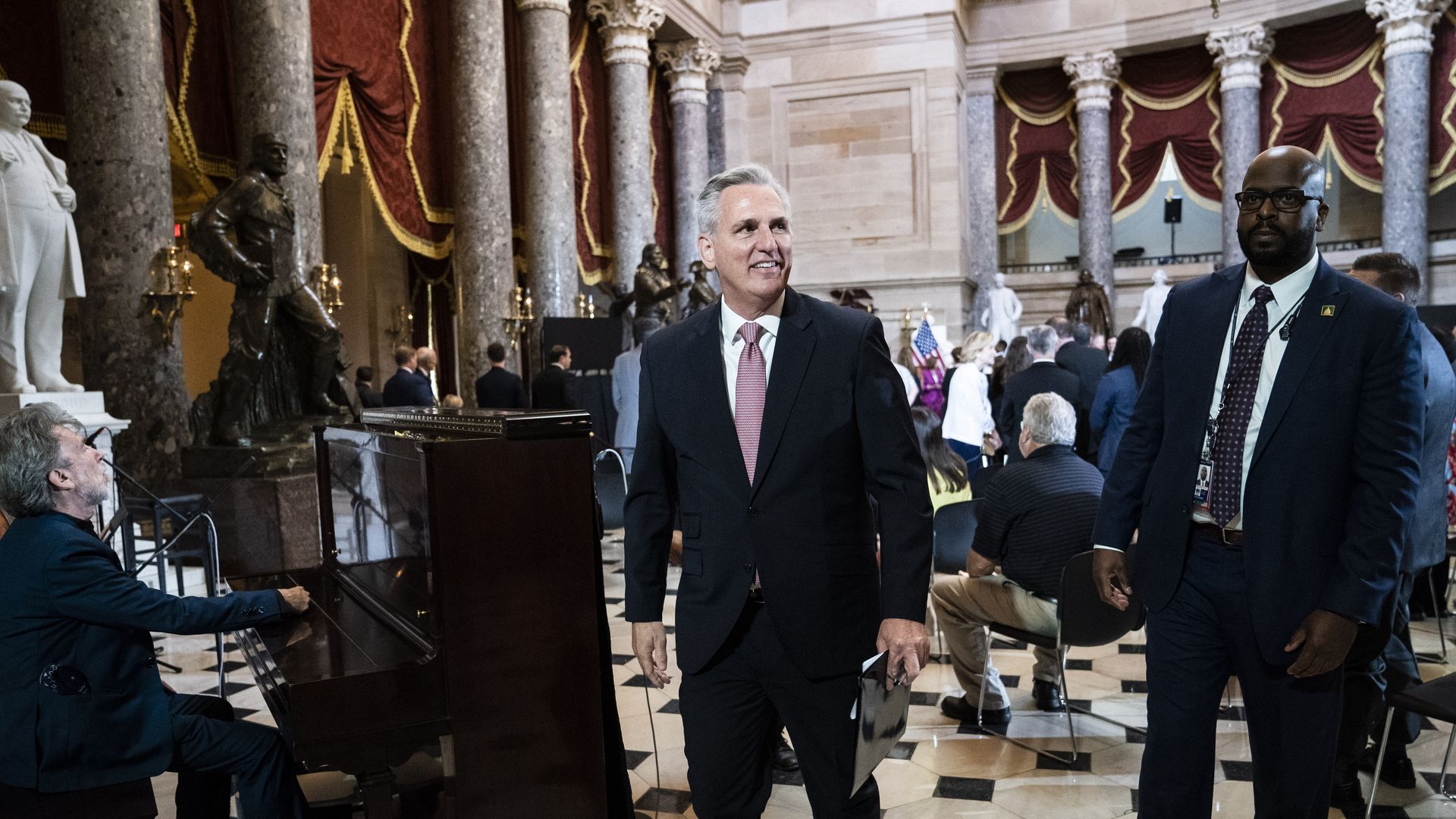House Minority Leader Kevin McCarthy, wearing a dark gray suit, white shirt and red-and-white tie, attends a memorial service in the Capitol's statuary hall.