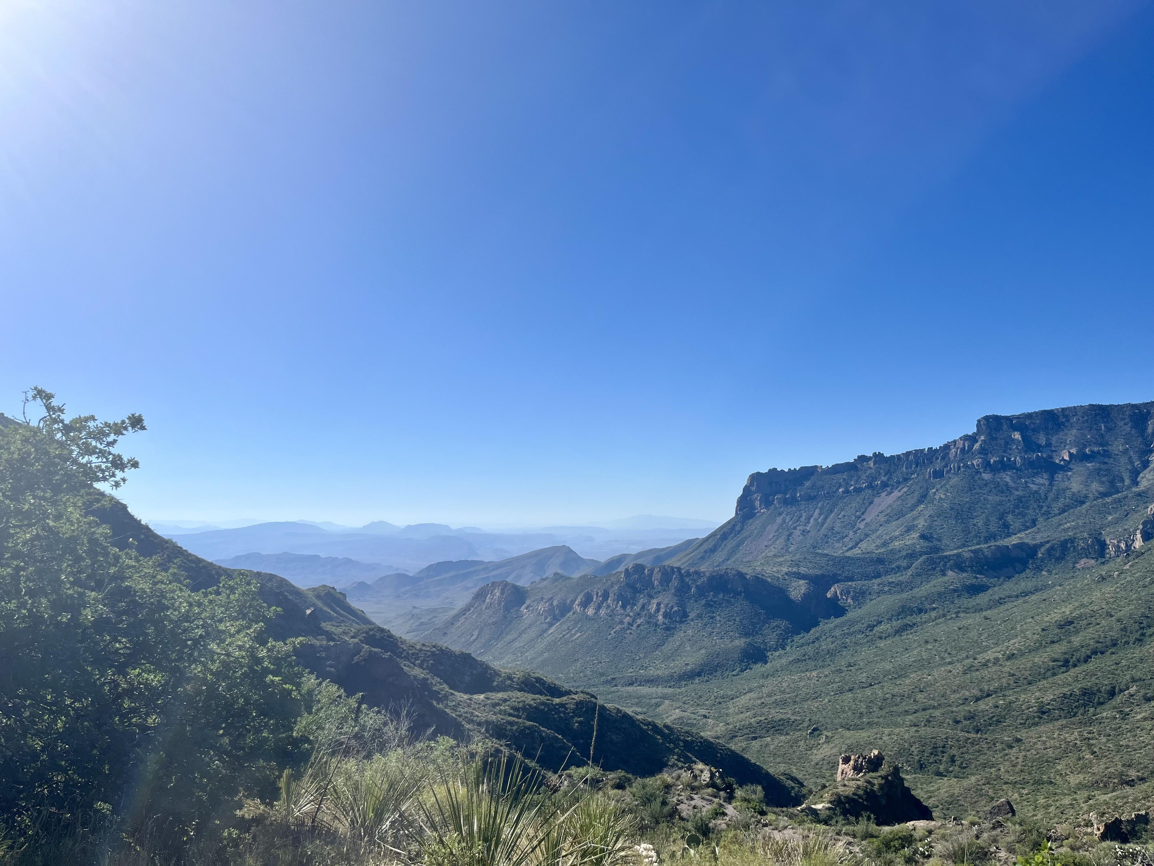 A view of green desert mountains against a blue sky.