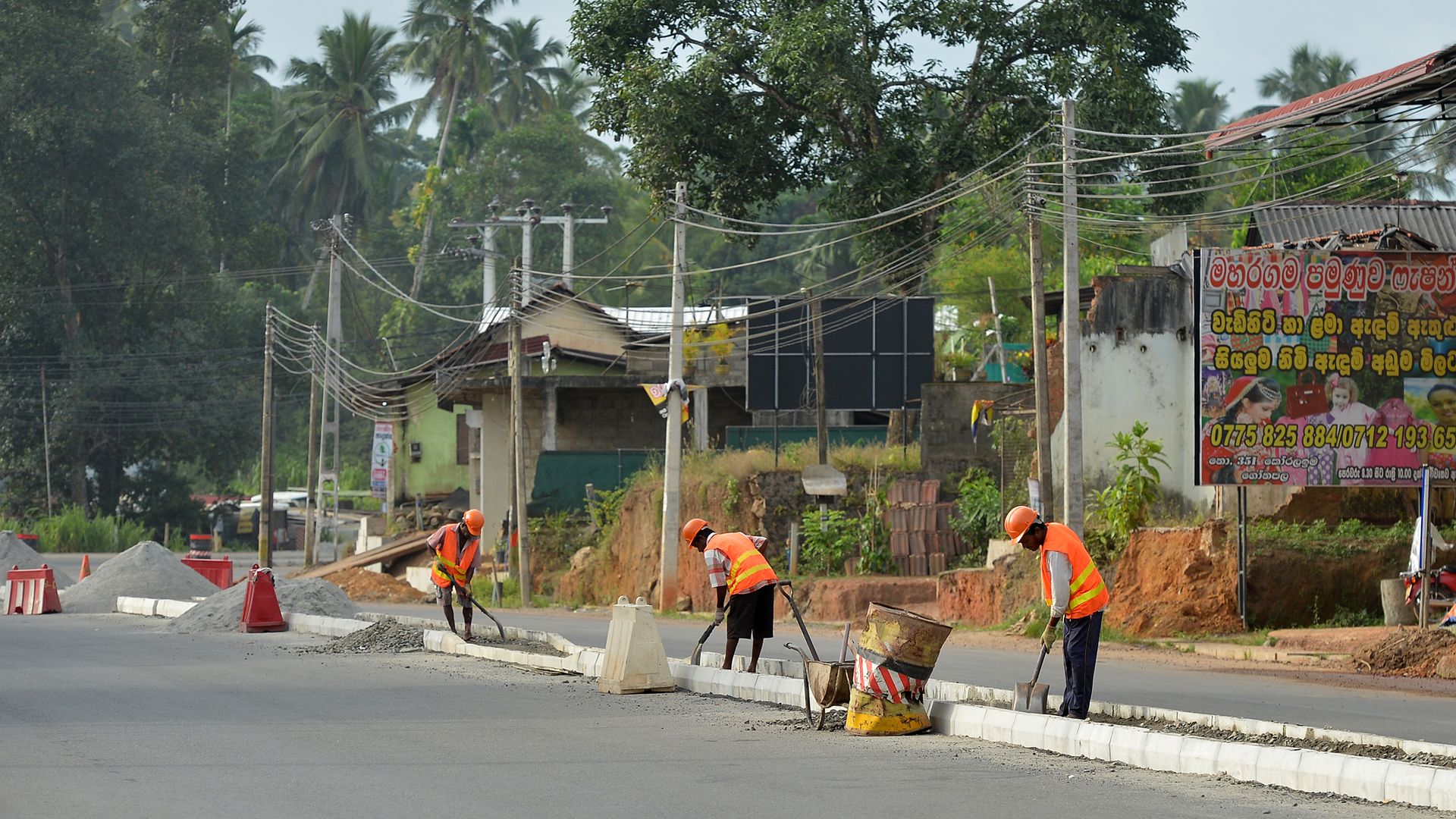 Sri Lankan road construction workers construction labourers works along a road in Colombo on August 5, 2018. 
