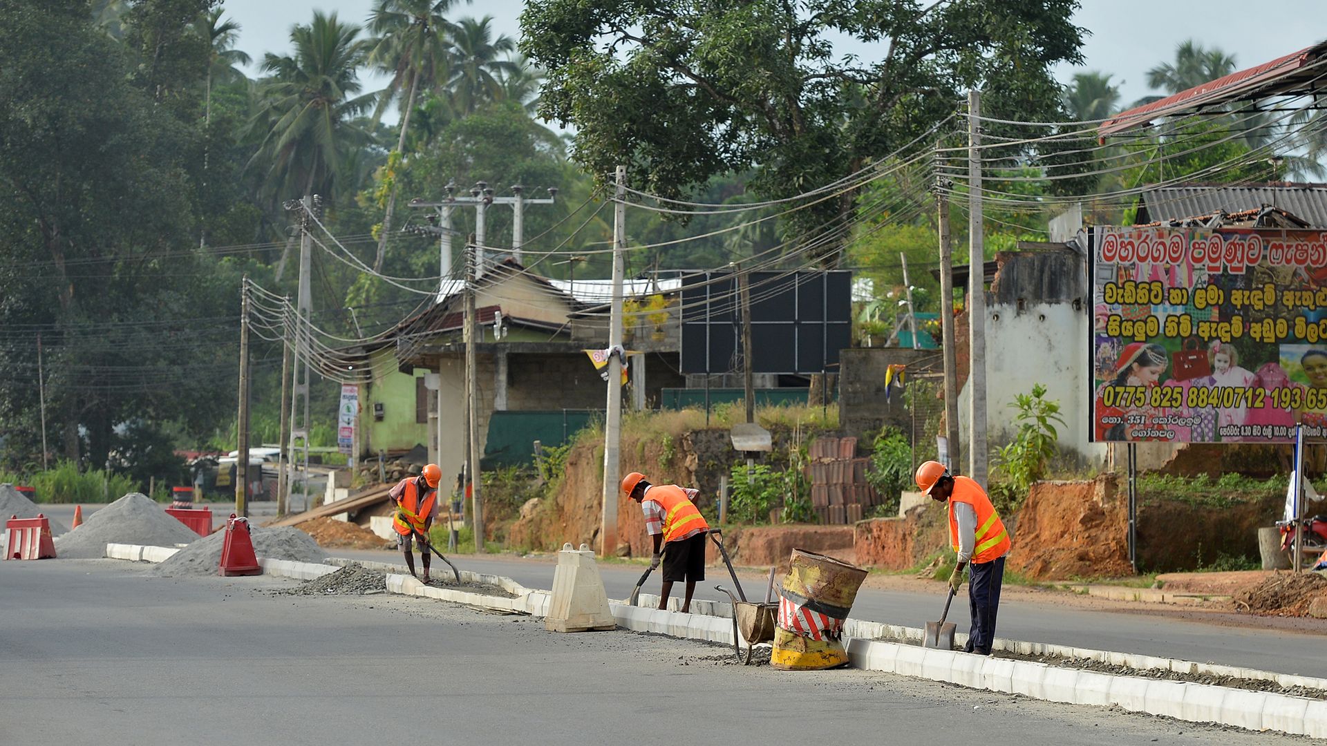 Sri Lankan road construction workers construction labourers works along a road in Colombo on August 5, 2018.