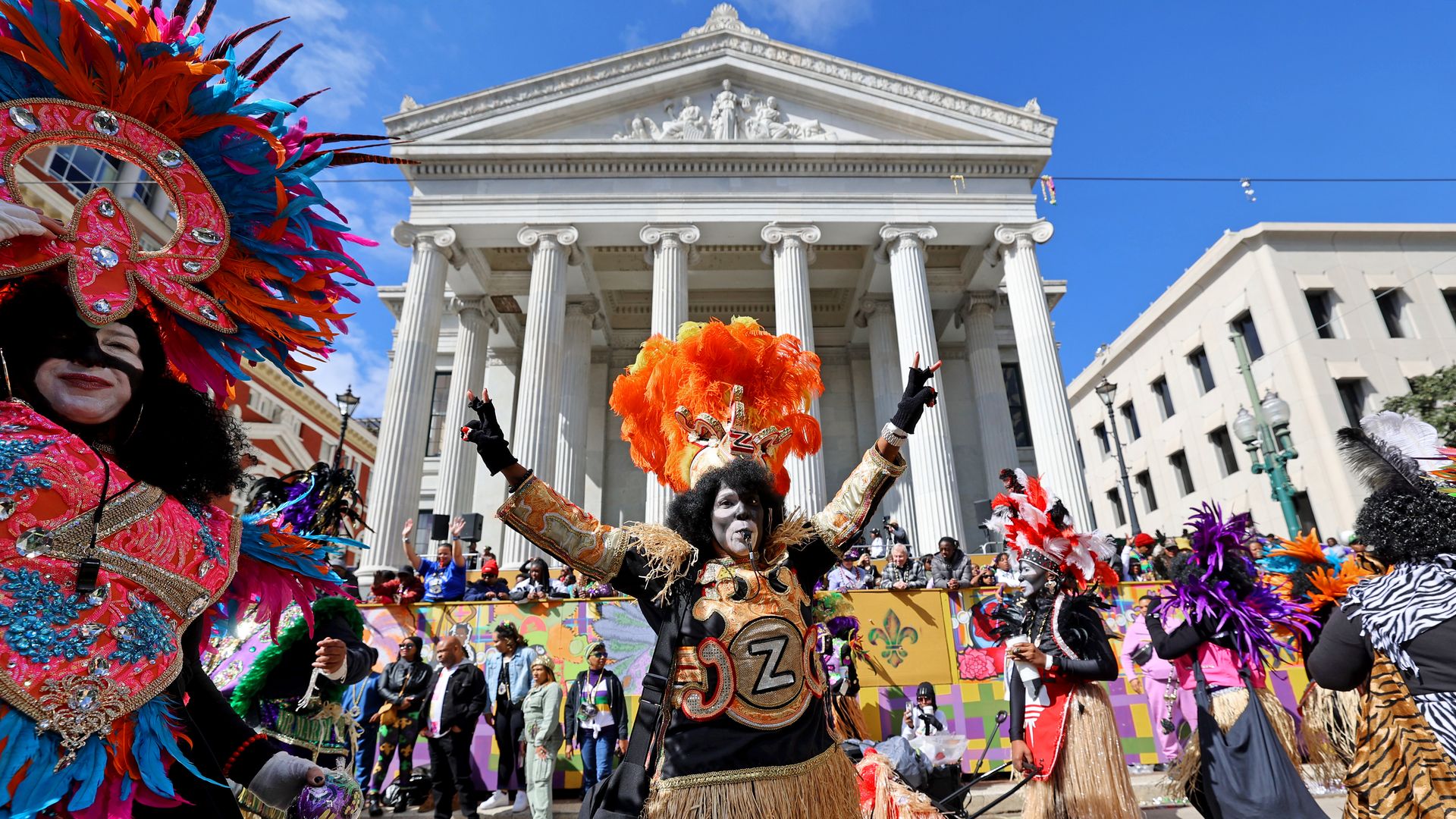 A Zulu warrior blows a whistle with both arms held high as the Zulu parade marches past Gallier Hall on Mardi Gras.
