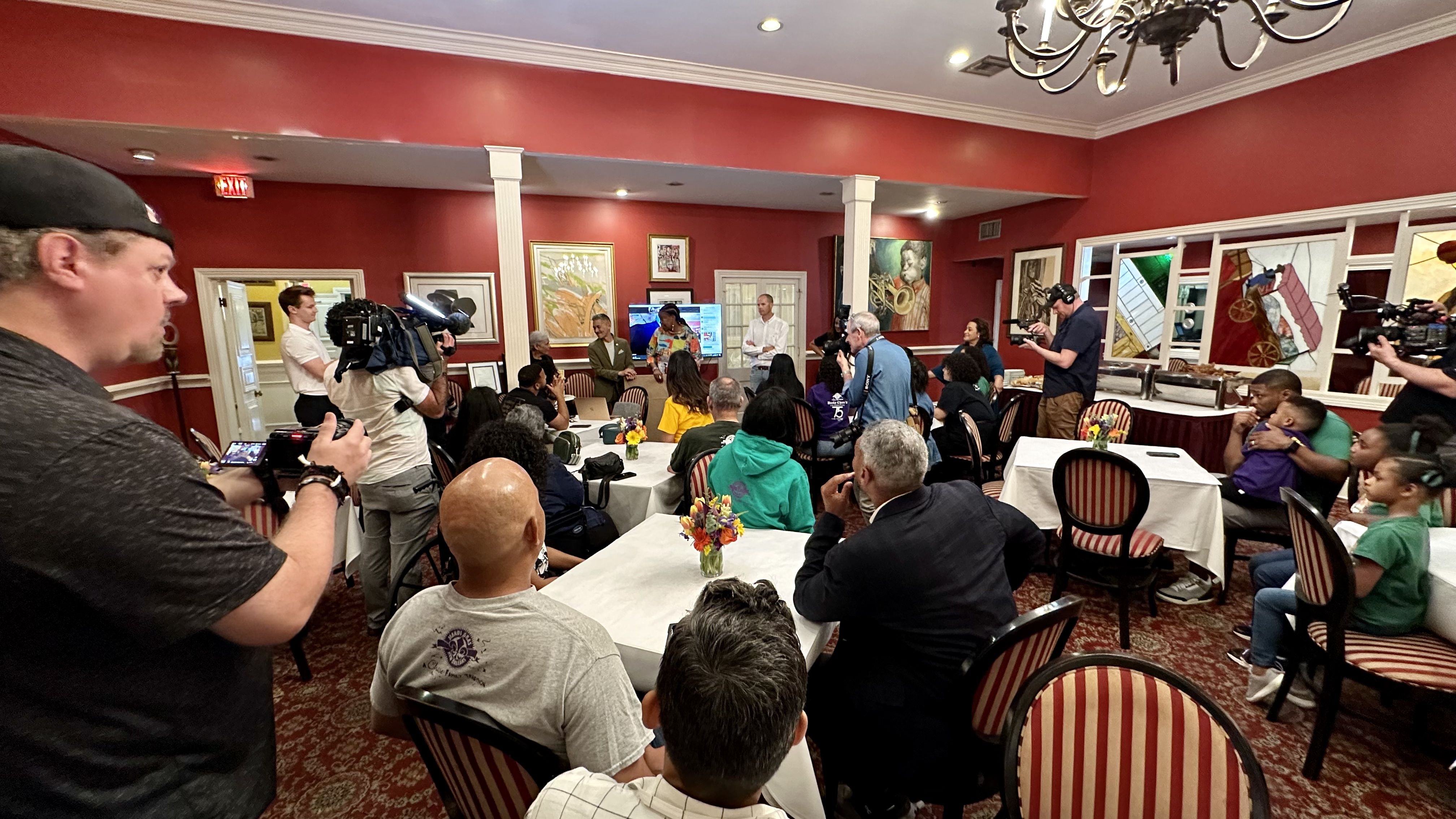 Photo shows the inside of the Dooky Chase dining room with family members at tables.