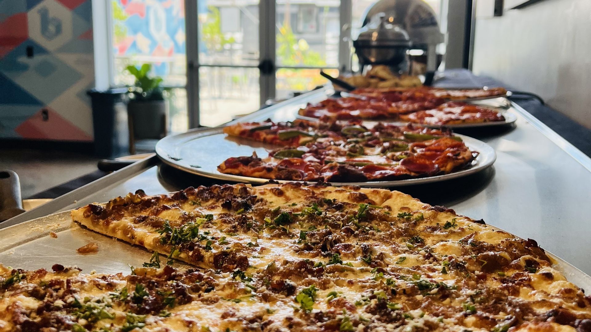 a table filled with pizzas and other food trays 