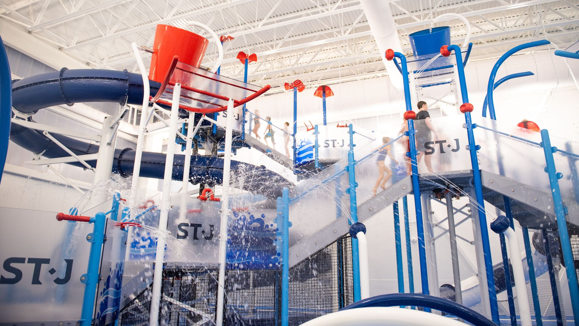 An indoor water park with a spiraling slide and water buckets.