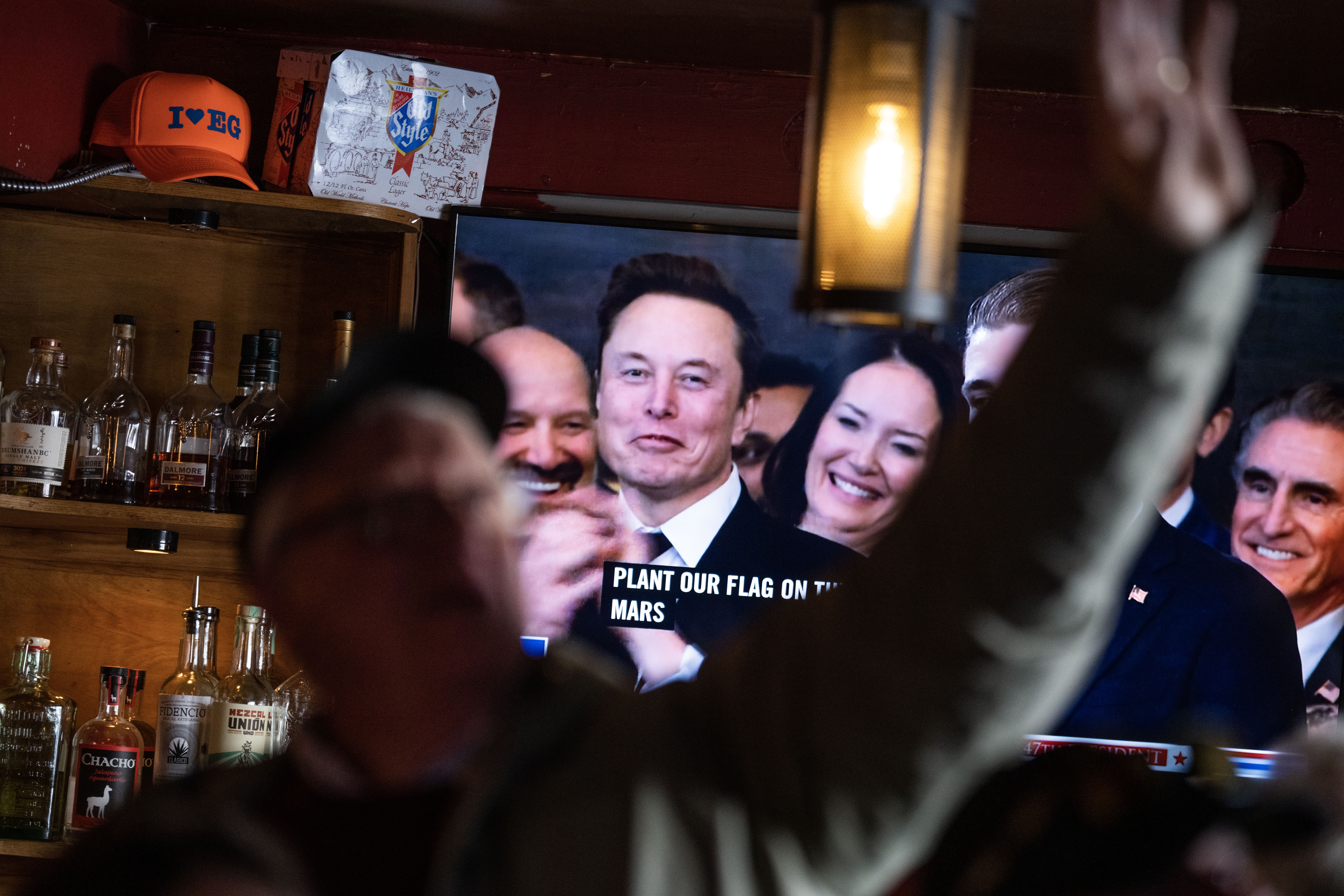 People inside a D.C. bar with Elon Musk on the TV screen