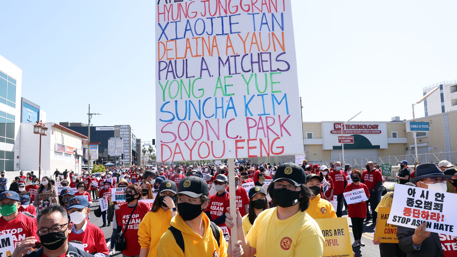 Photo of a crowd of protesters carrying Stop Asian Hate signs, as well as a sign with Atlanta victims' names