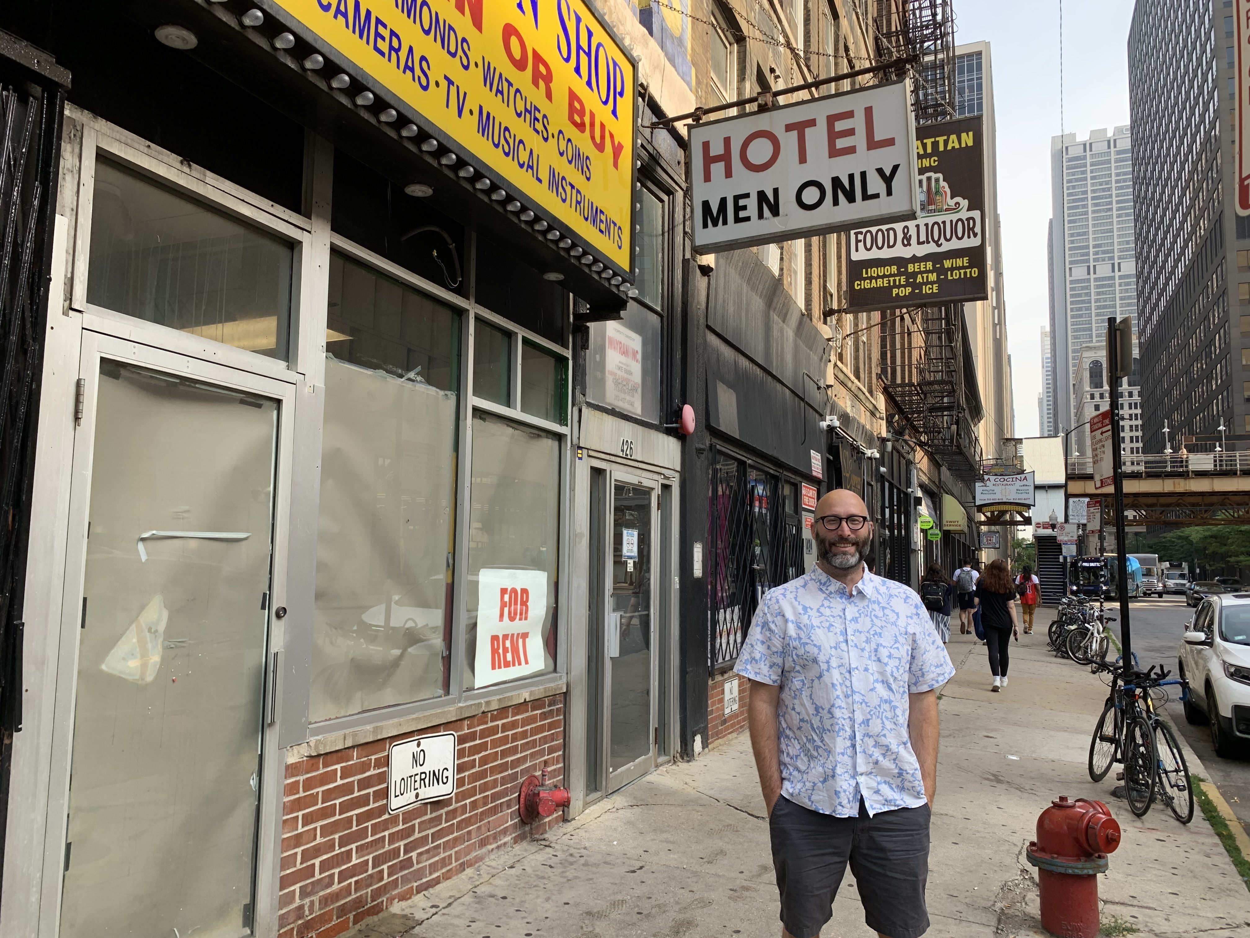 Photo of a man standing in front of a sign that says  Hotel Men Only 