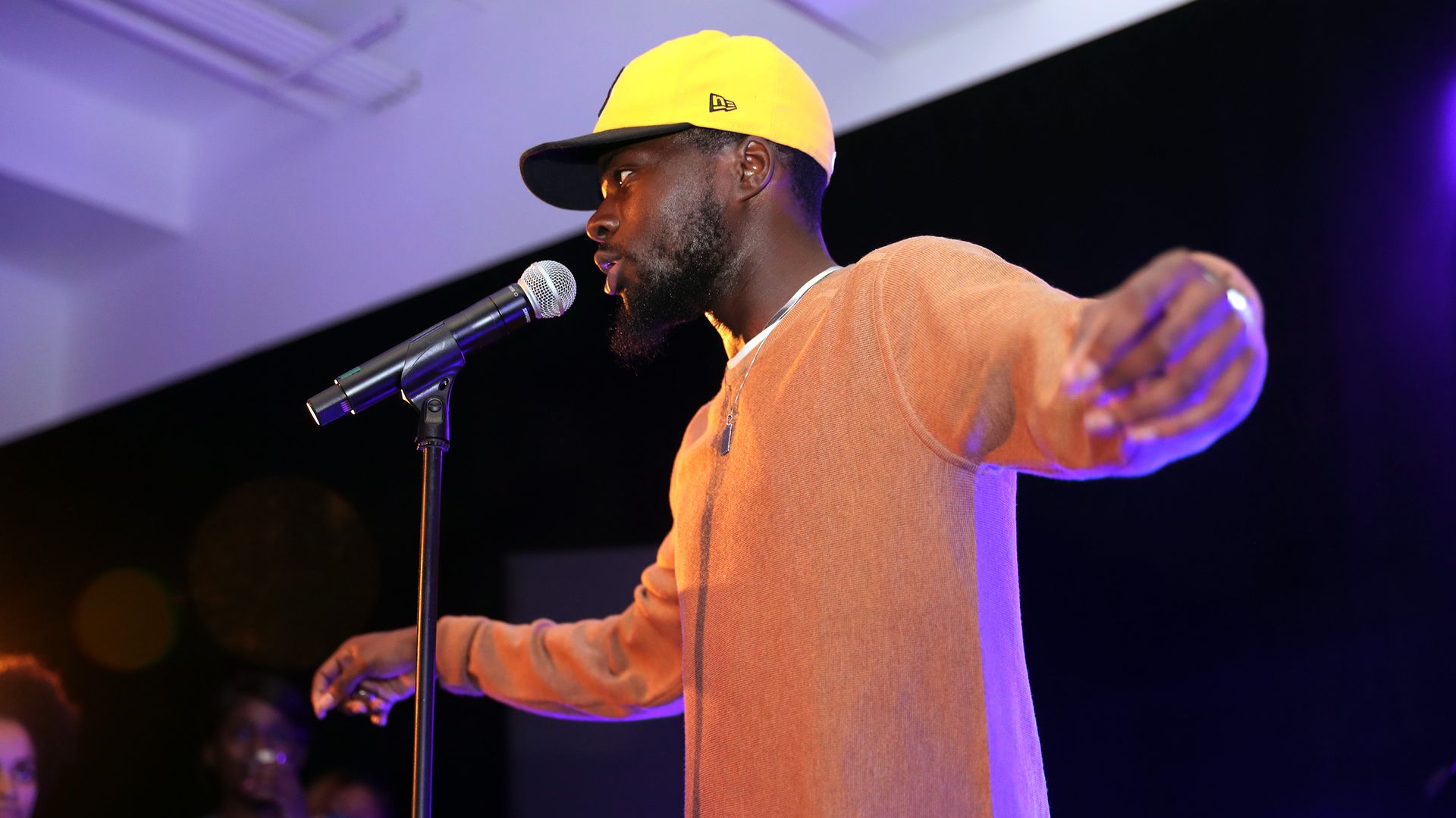 Photo of a man talking into a microphone on a stage 