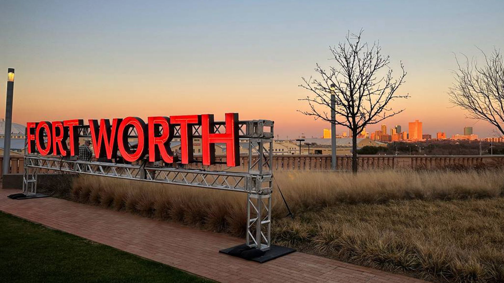 an orange sign that reads "FORT WORTH" with a skyline behind it in the distance