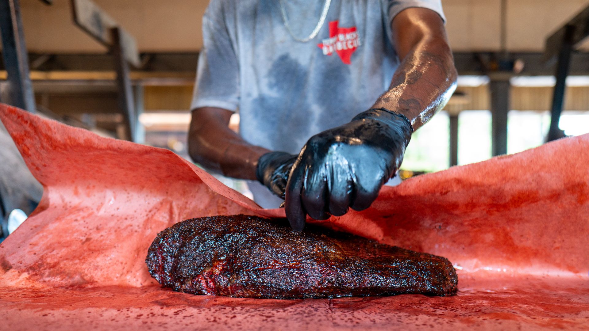 A brisket getting wrapped at a bbq joint.
