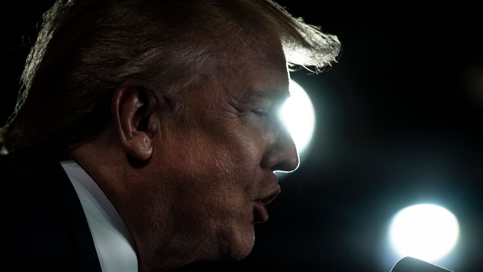 This image is a profile of Donald Trump speaking into a microphone. 