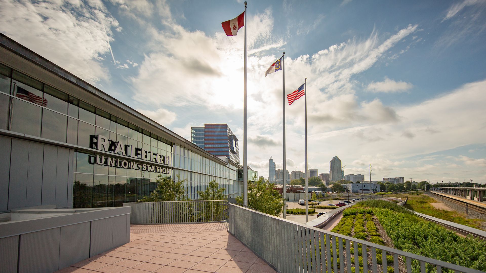The Raleigh Union Station with the sun reflecting off its windows. The downtown Raleigh skyline can be seen in the background. 