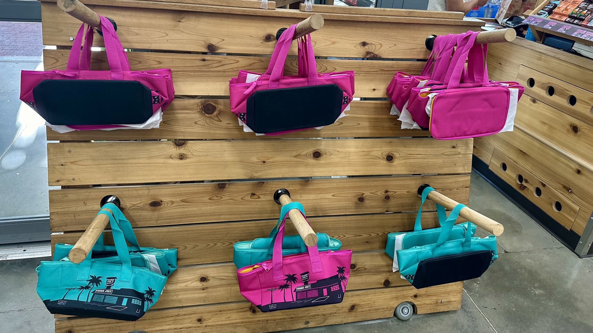 Magenta and teal cooler bags on display at a Trader Joe's store