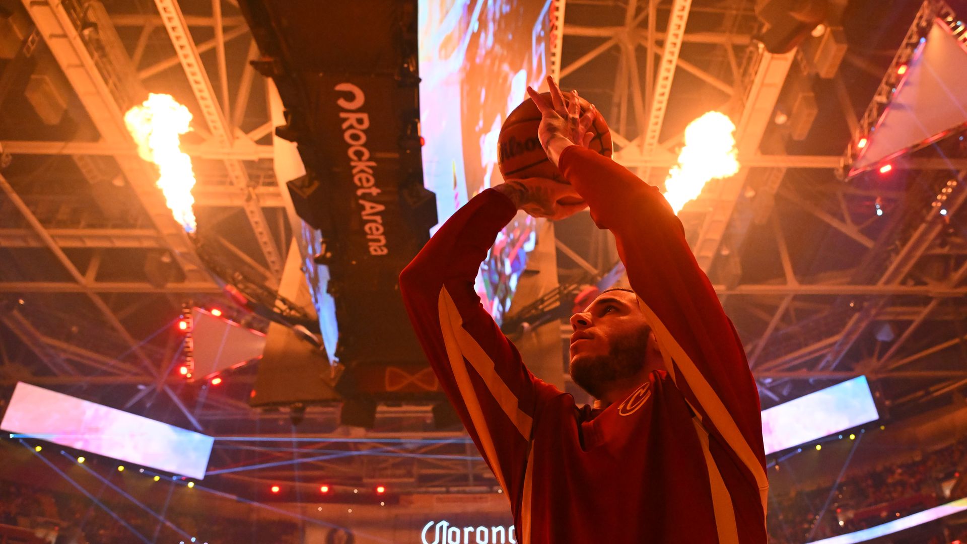 NBA player in red warmups shoots beneath flames from a jumbotron. 