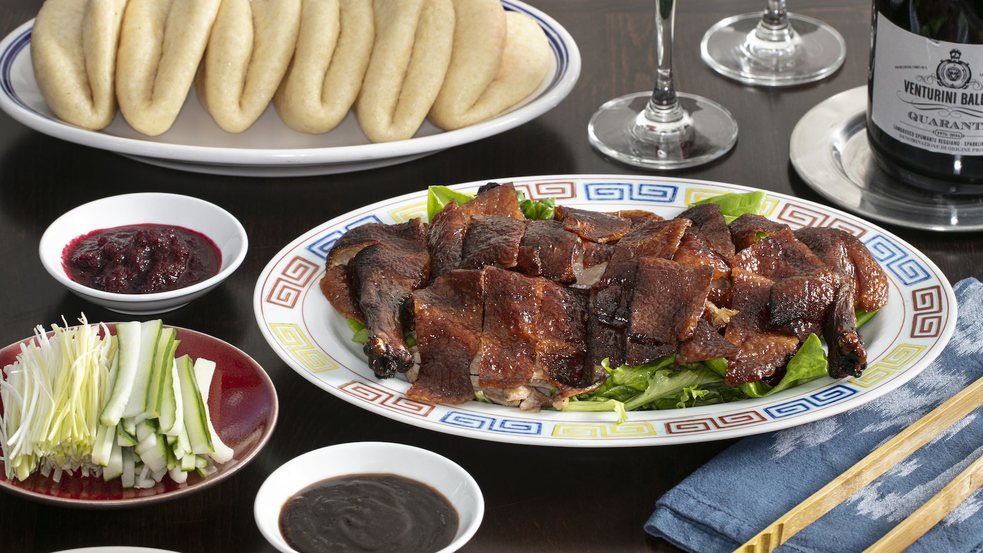 A plate with Peking duck, pancakes and wine
