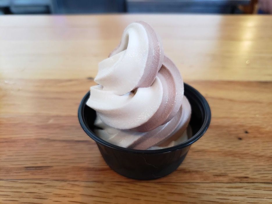 A purple and white soft serve swirl in a black cup.