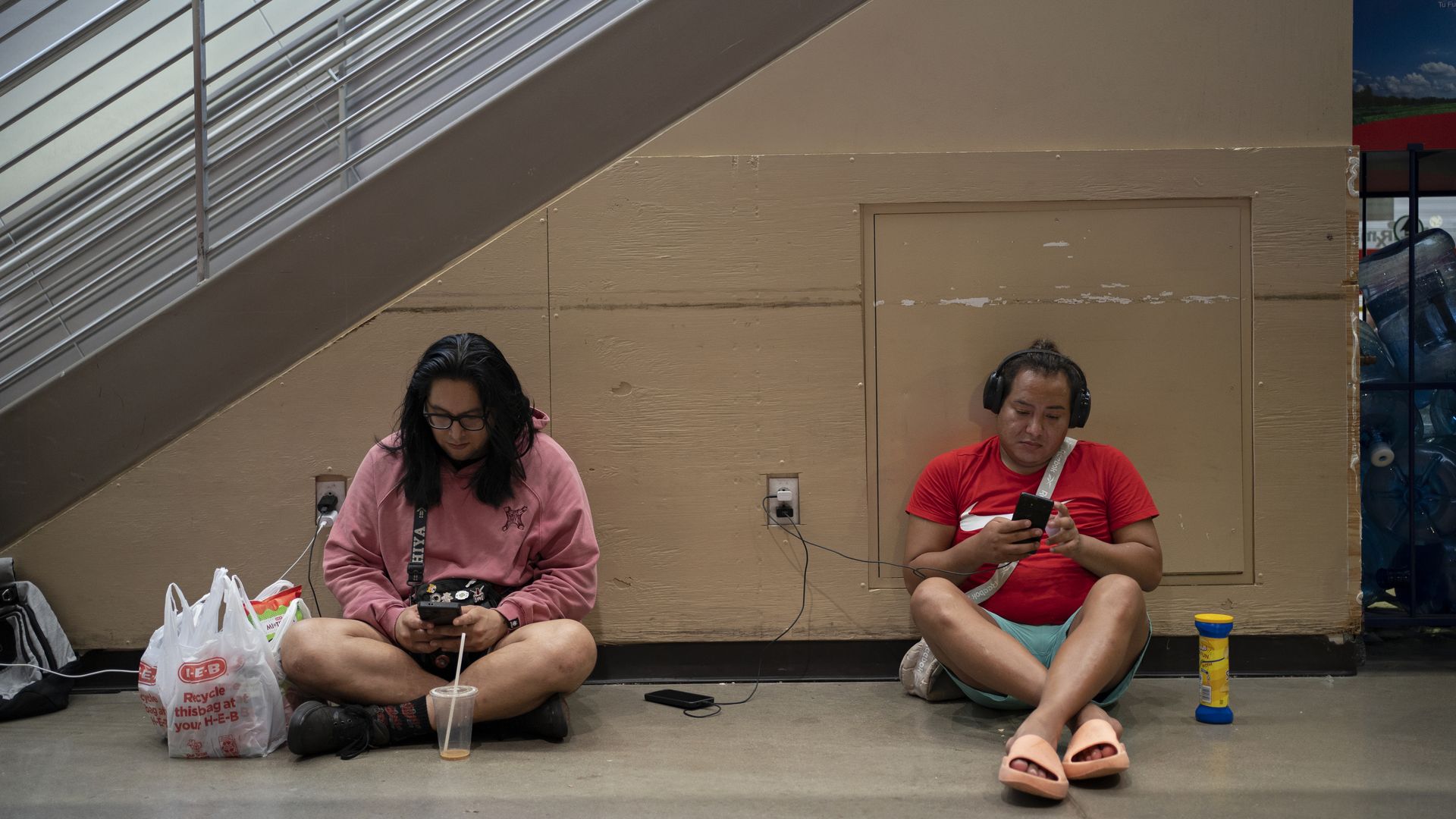 A photo of two people sitting down against stairs.