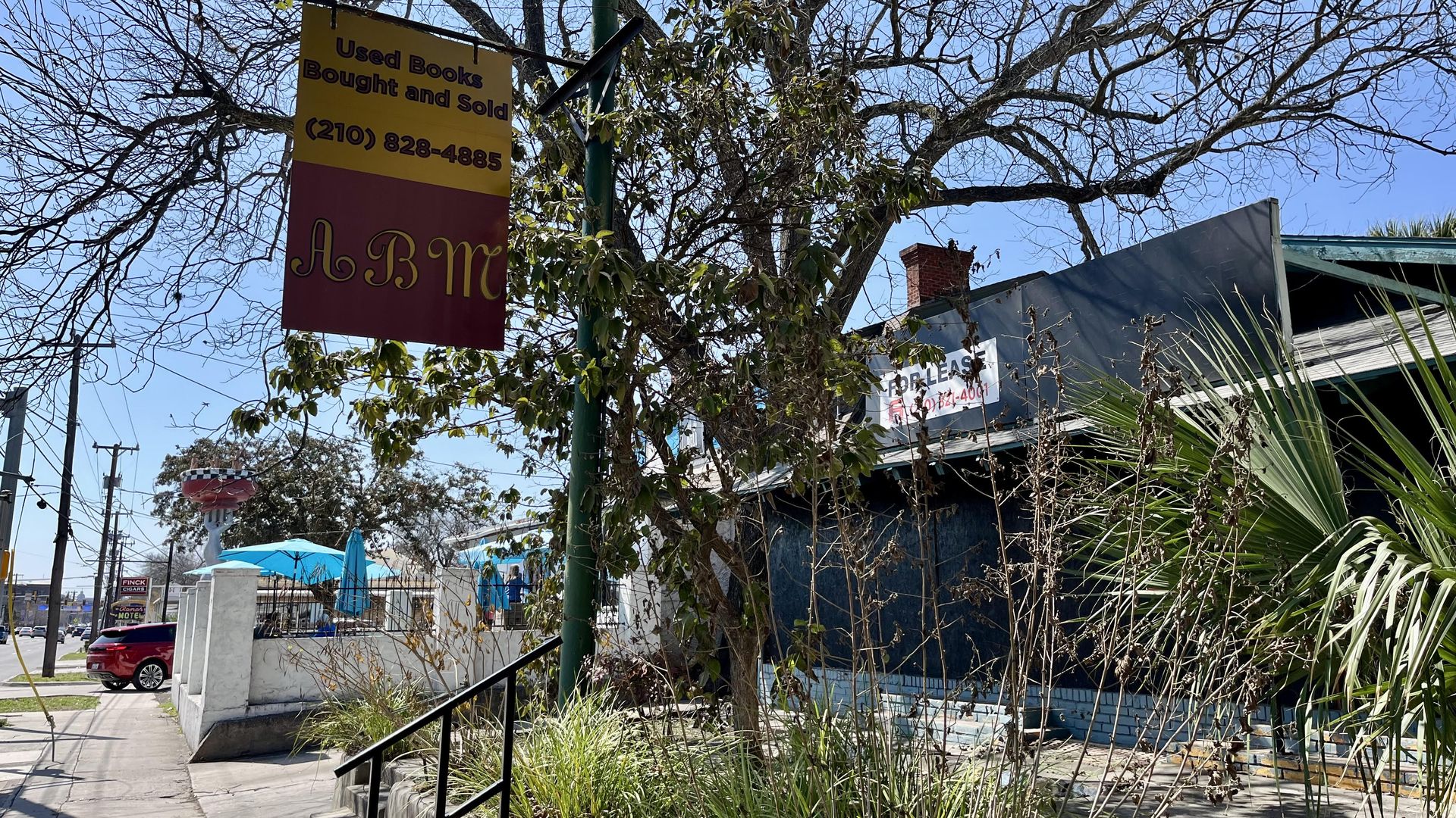 A "for lease" sign on Broadway next door to a bustling local deli.