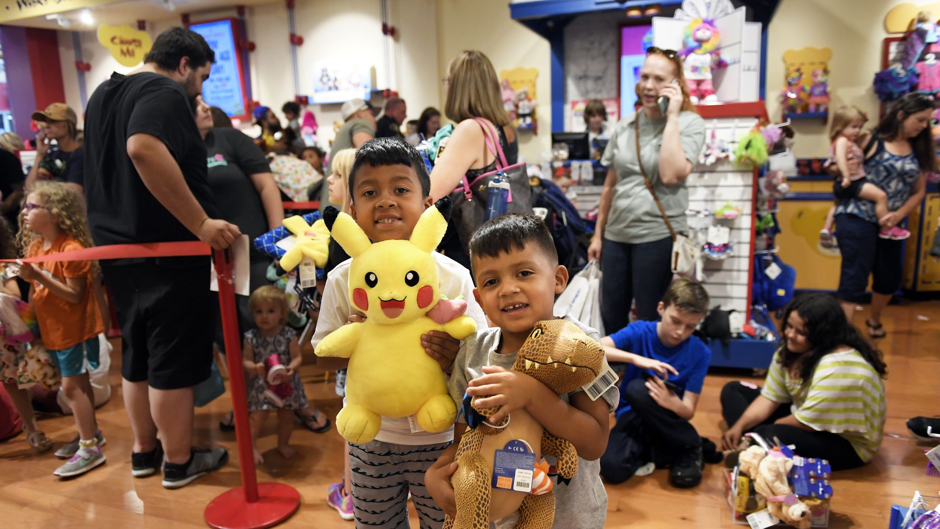 Two children pose with their plush toys at a Build-A-Bear store.